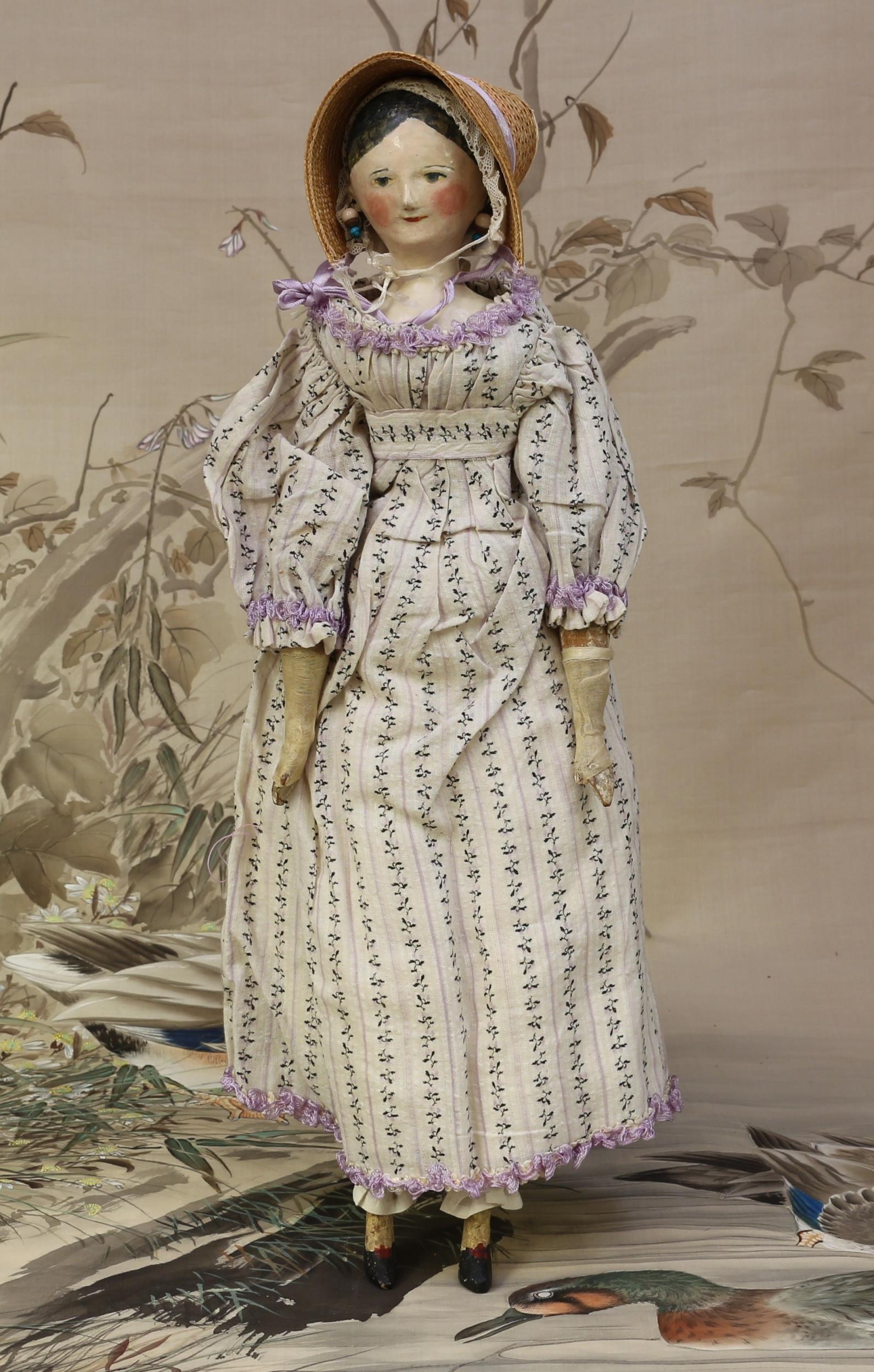 A mid 19th century carved and painted wooden doll, the carved and painted head with painted features including black hair, blue eyes, red lips and blush cheeks, pierced ears,  jointed peg construction body, white painted forearms, painted lower legs with shaped feet, 42cm high