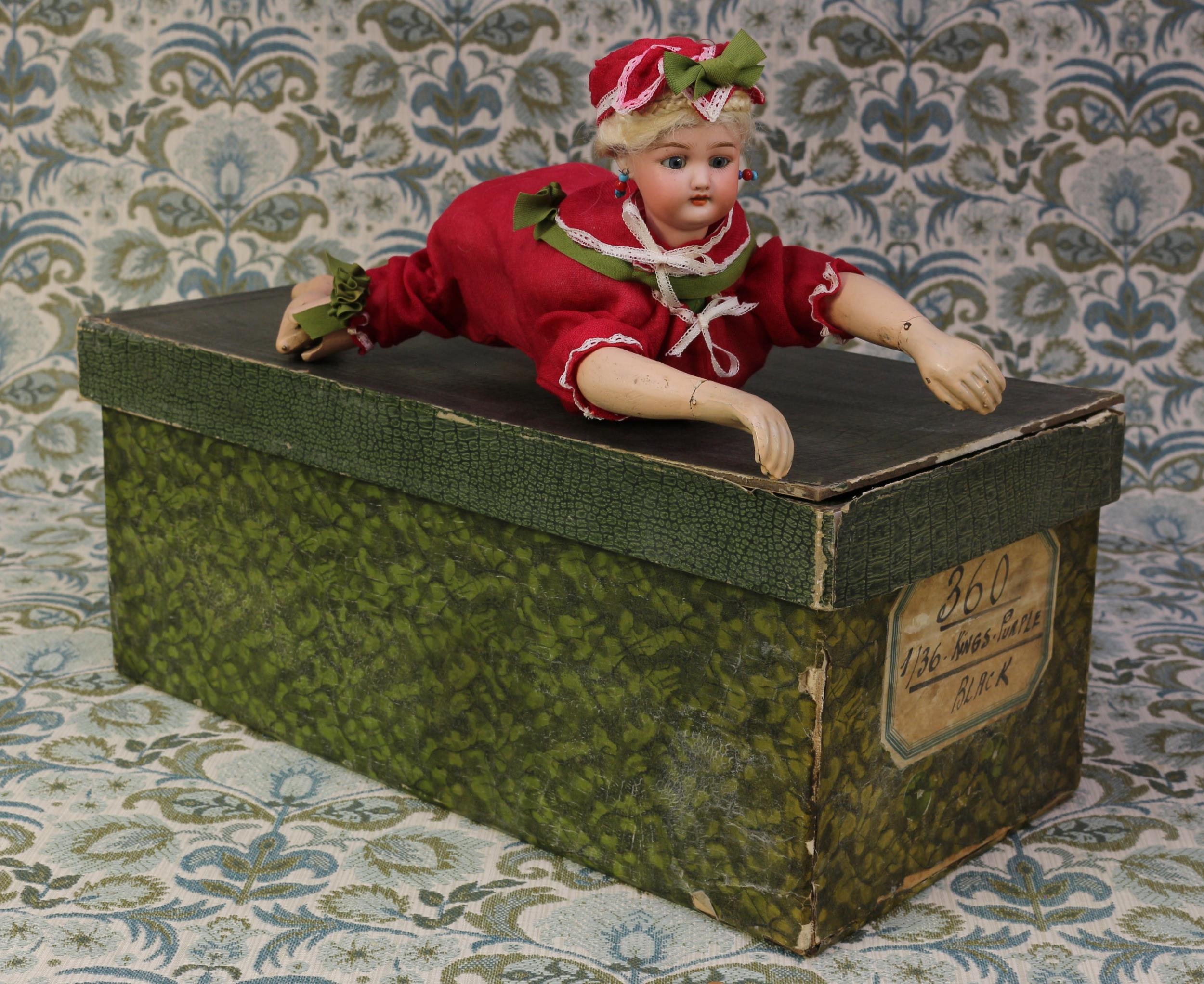 A Simon & Halbig (Germany) bisque head 'Ondine' automaton swimming doll, the bisque head with fixed blue glass eyes, painted features including brown feathered eyebrows and fine eyelashes, open mouth revealing teeth, blonde wig, pierced ears, impressed marks '1079 HALBIG S.H. 8', the torso fitted with a fixed key mechanism, 40cm long, displayed in a rectangular cardboard box with lid