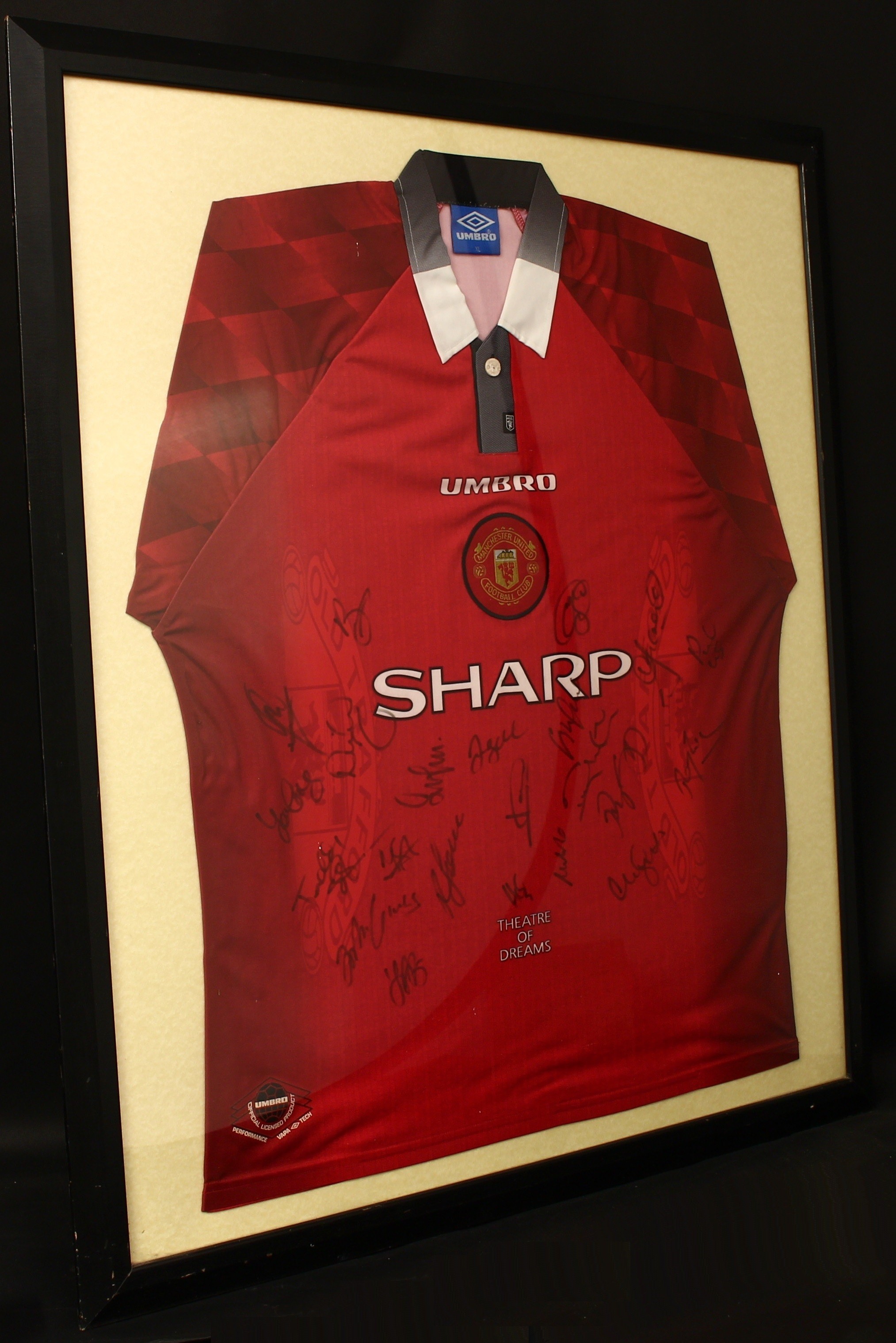 Sport, Football, Autographs, Manchester United F.C. (The Red Devils) - a 1996-1998 'Theatre of Dreams' home shirt, Umbro XL size with Sharp sponsor, signed in black marker pen by twenty three players and officials, various signatures from 1998/1999 Treble winning squad including David BECKHAM, Teddy SHERINGHAM, Peter SCHMEICEL, Roy KEANE, Ryan GIGGS, Sir Alex FERGUSON etc, presented in a glazed frame  Provenance - the signed shirt is accompanied with a letter from Manchester United F.C. and is dated 29th October 1999, the letter has a reference number and appears to be from Sir Alex Ferguson CBE with his facsimile signature.