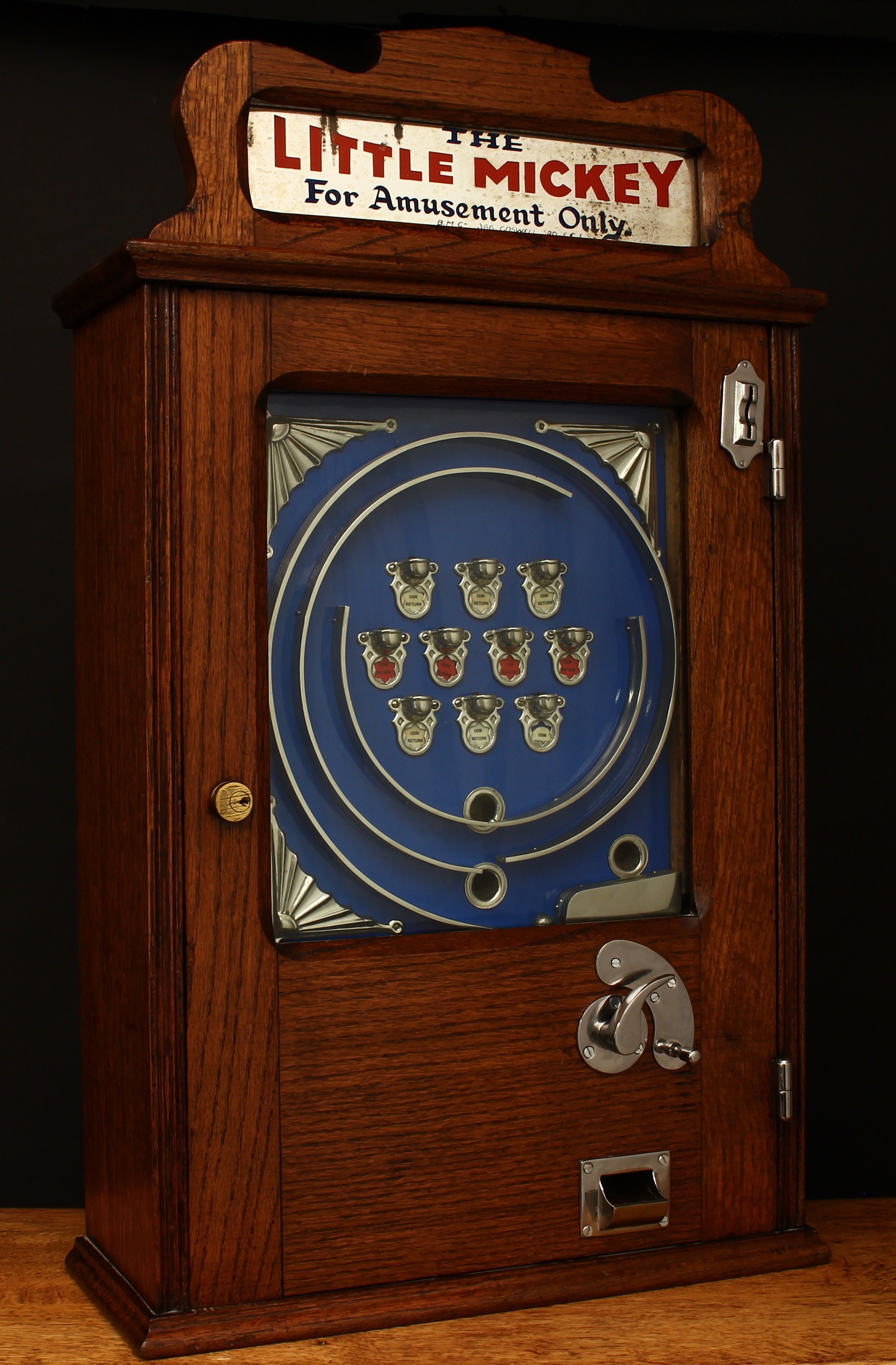 A 1930's B.M. Co. (British Manufacturing Company) The Little Mickey 'Allwins' mechanical penny slot arcade/amusement machine with automatic payout, the rectangular shaped oak case with mirrored top flash intact, the inner blue back plate with trademark sunray corner spandrels and ten cups, curved trigger with crescent stop plate, glazed hinged door, 78cm high, 46cm wide, 19cm deep