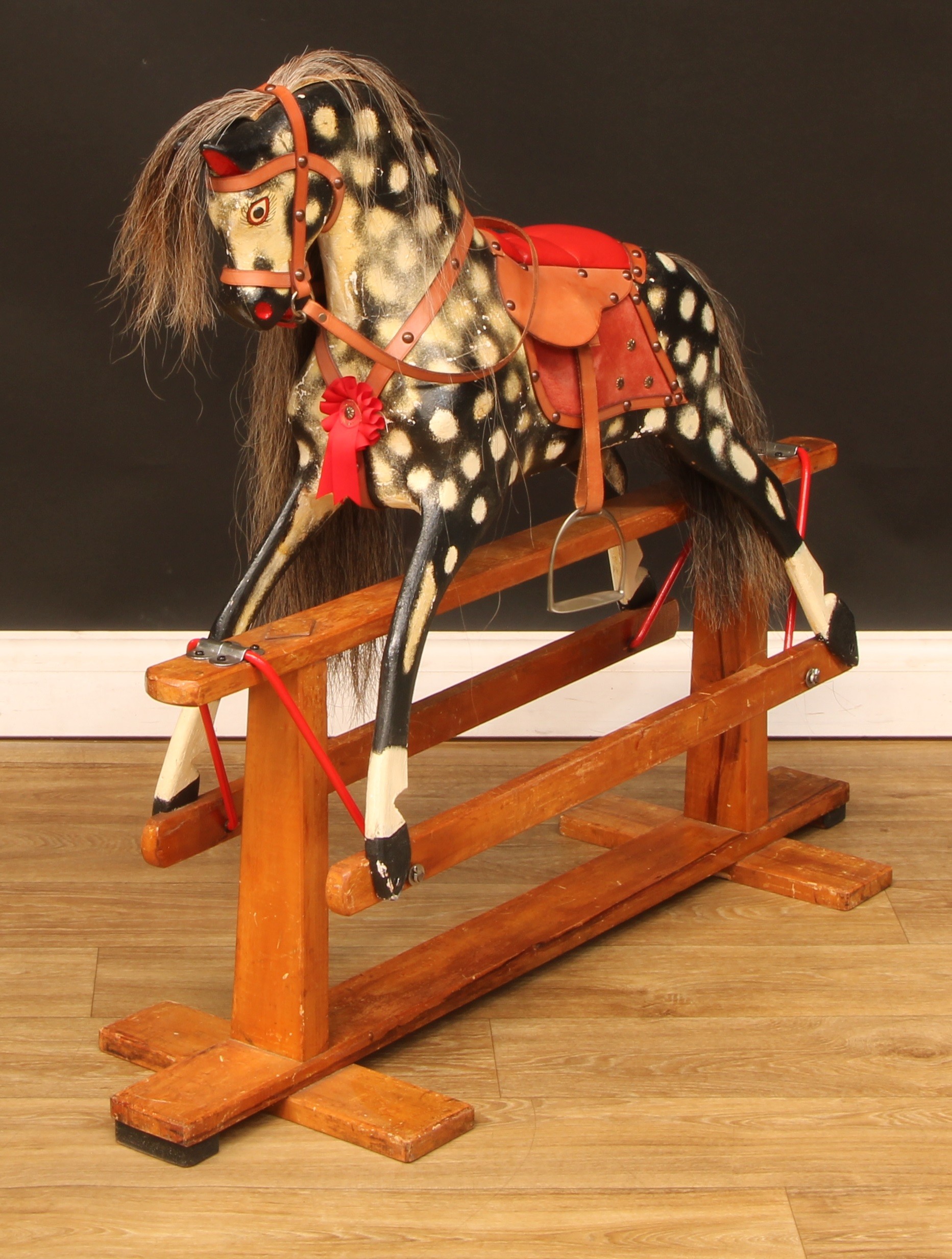 A J.Collinson and Sons rocking horse on safety stand, the carved, gesso and painted dappled horse with pricked ears, flared nostrils and open mouth, pin type eyes, trademark vertical tapered rectangular pillars and diamond shaped hardboard pieces on the top bar of the stand, 90cm high, 106cm long, c.1965  Provenance - accompanied with various paperwork and invoices, the rocking horse was previously professionally and sympathetically restored by Stevenson Brothers in 1998