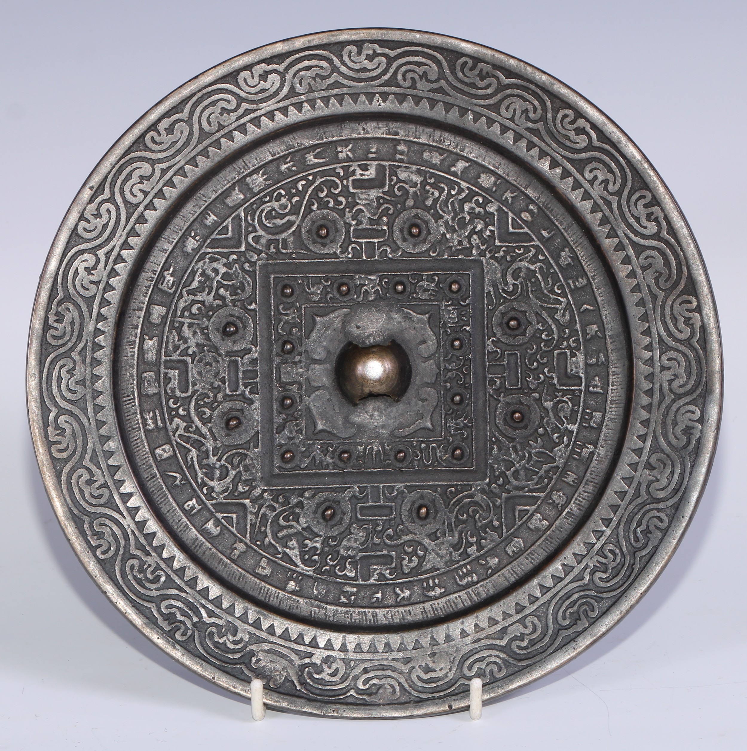 A Chinese bronze Archaic hand mirror, well cast in the typical Han Dynasty manner with TLV symbolism, 23.5cm diam  Provenance: Known in the vendor's family for over fifty years, and used by his father as a dish for nuts.