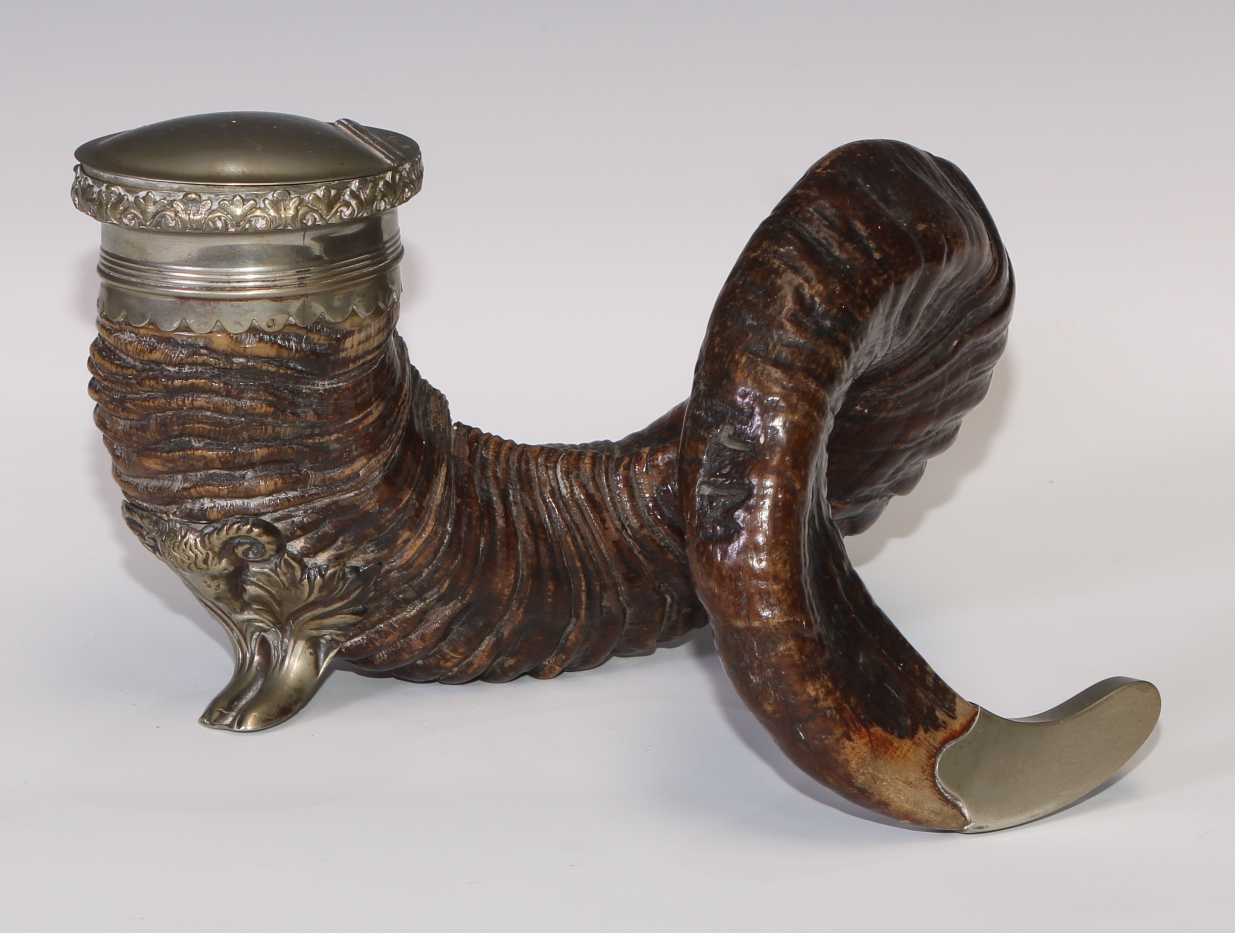 A 19th century ram's horn table snuff mull, the Britannia metal mount with hinged cover and foliate border, caprine mask and hoof support, 23cm wide, c.1880