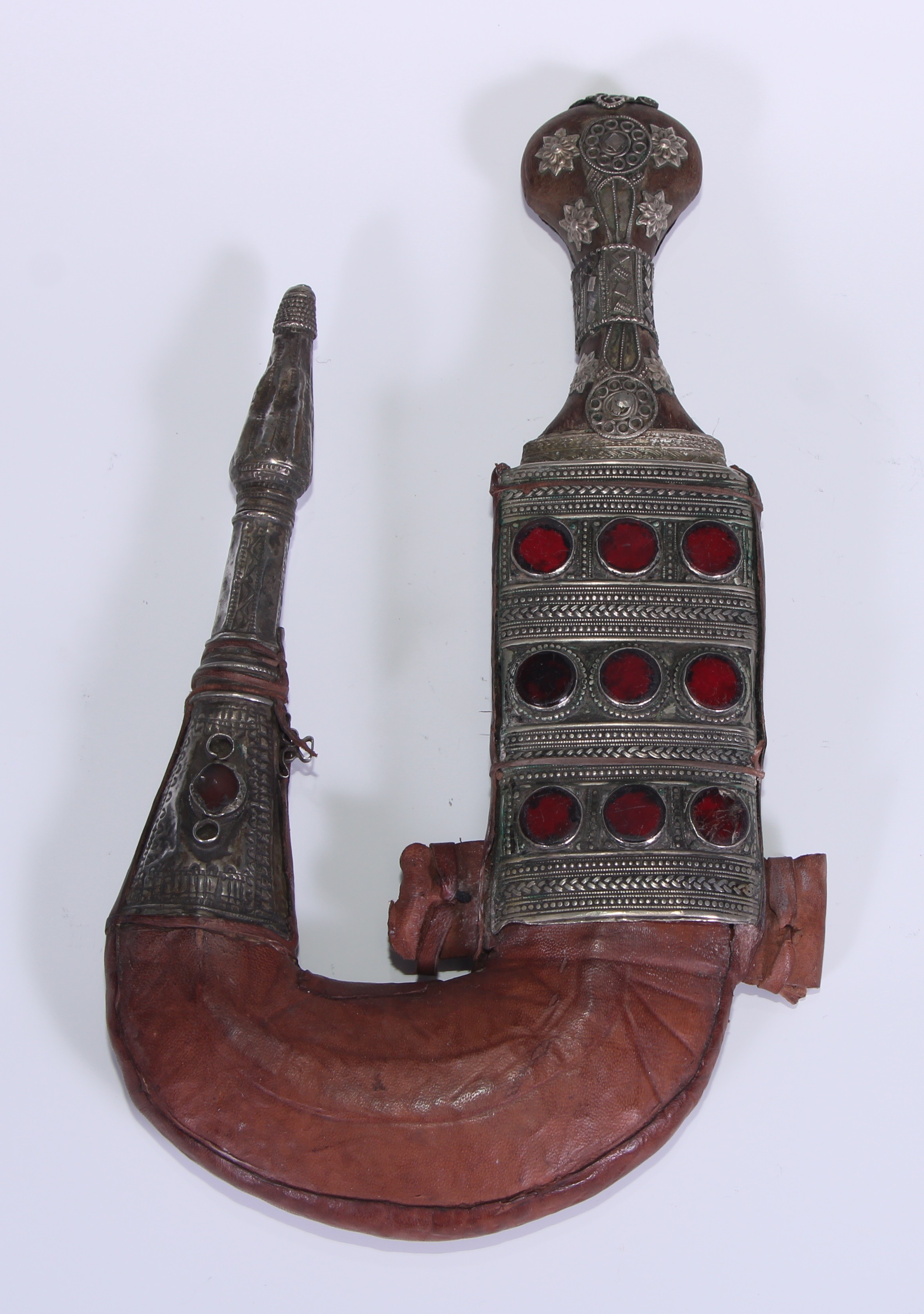 A Middle Eastern silver coloured metal mounted jambiya dagger, 18.5cm curved blade with central ridge, the scabbard collet set with rows of red glass roundels, 33cm long