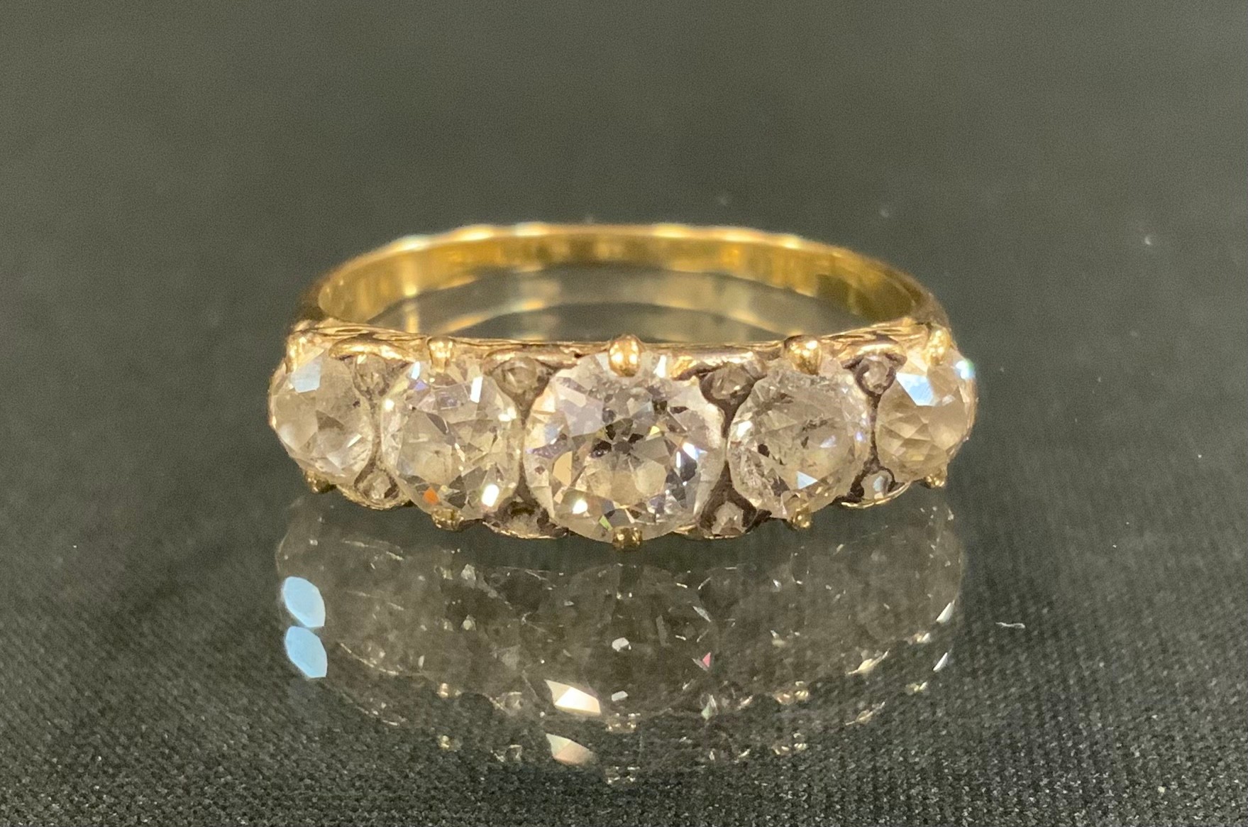 An Edwardian old cut diamond ring, linear set with five graduated diamonds, total estimated diamond weight approx 1.5ct, unmarked gold coloured metal shank, size S, 3.4g gross