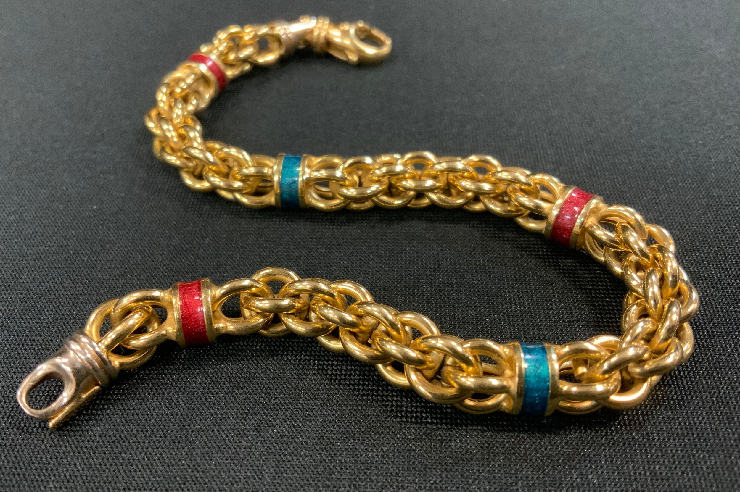 An 18ct gold fancy link bracelet divided by five alternate enamelled bands in emerald green and ruby red, stamped 750, indistinct marks, 20.5cm long, 23.5g gross