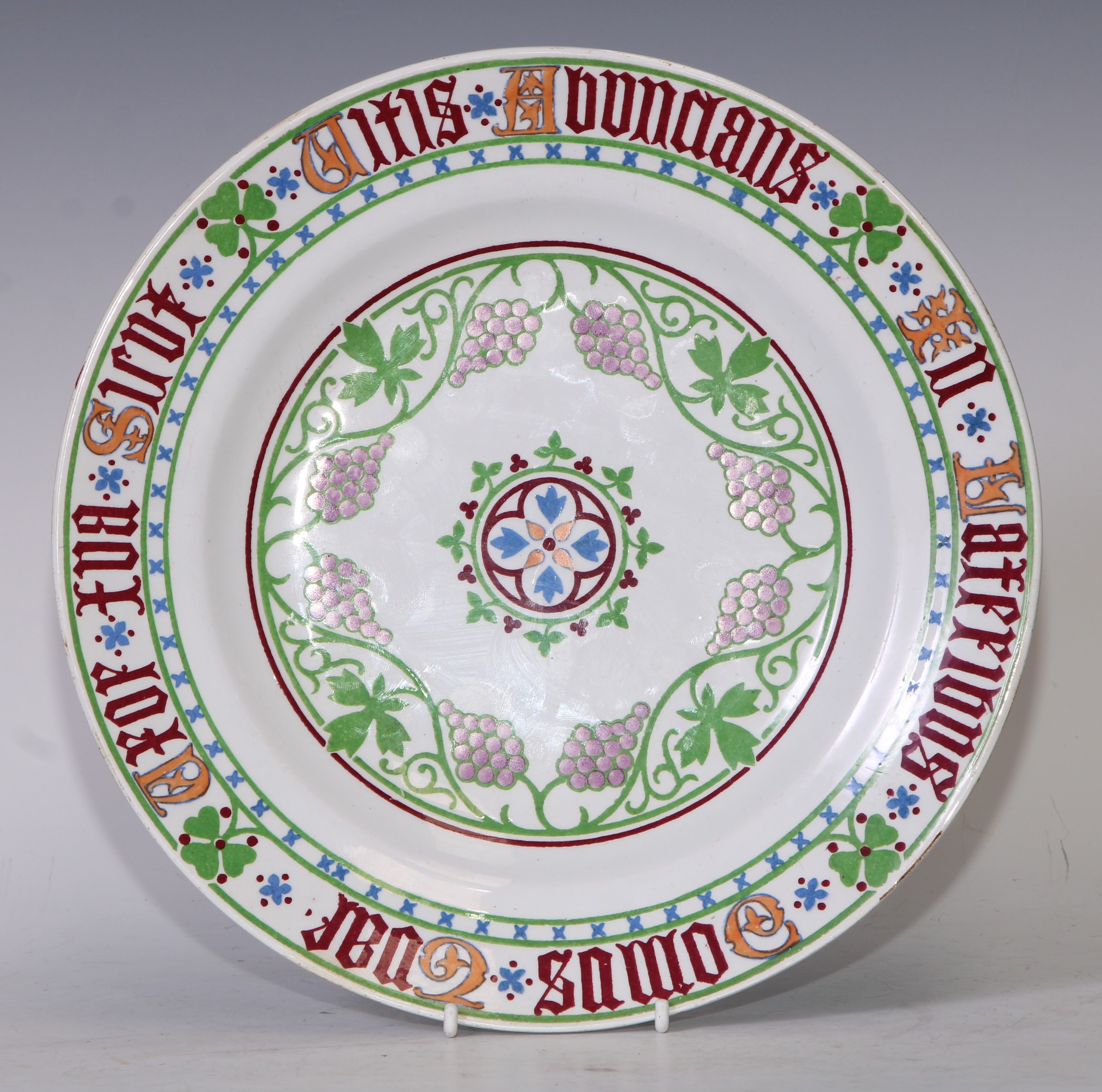 Augustus Welby Northmore Pugin (1812-1852) - a Minton and Hollins New Stone circular plate, designed by Pugin for the Palace of Westminster, with central Gothic roundel surrounded by scrolling grapes, the rim inscribed in Latin, 26cm diam,   impressed marks  The remaining service is stored at the Palace of Westminster, but not on public display. There are almost 200 pieces which were acquired in 1983 after being discovered in the Priest’s House, St Mary’s Roman Catholic Church, East Hendred by Reverend Anthony Fagan.  The service was originally used by Pugin and his family in their home, The Grange, in Ramsgate.  These are two of the three plates known to exist outside of the Palace of Westminster.