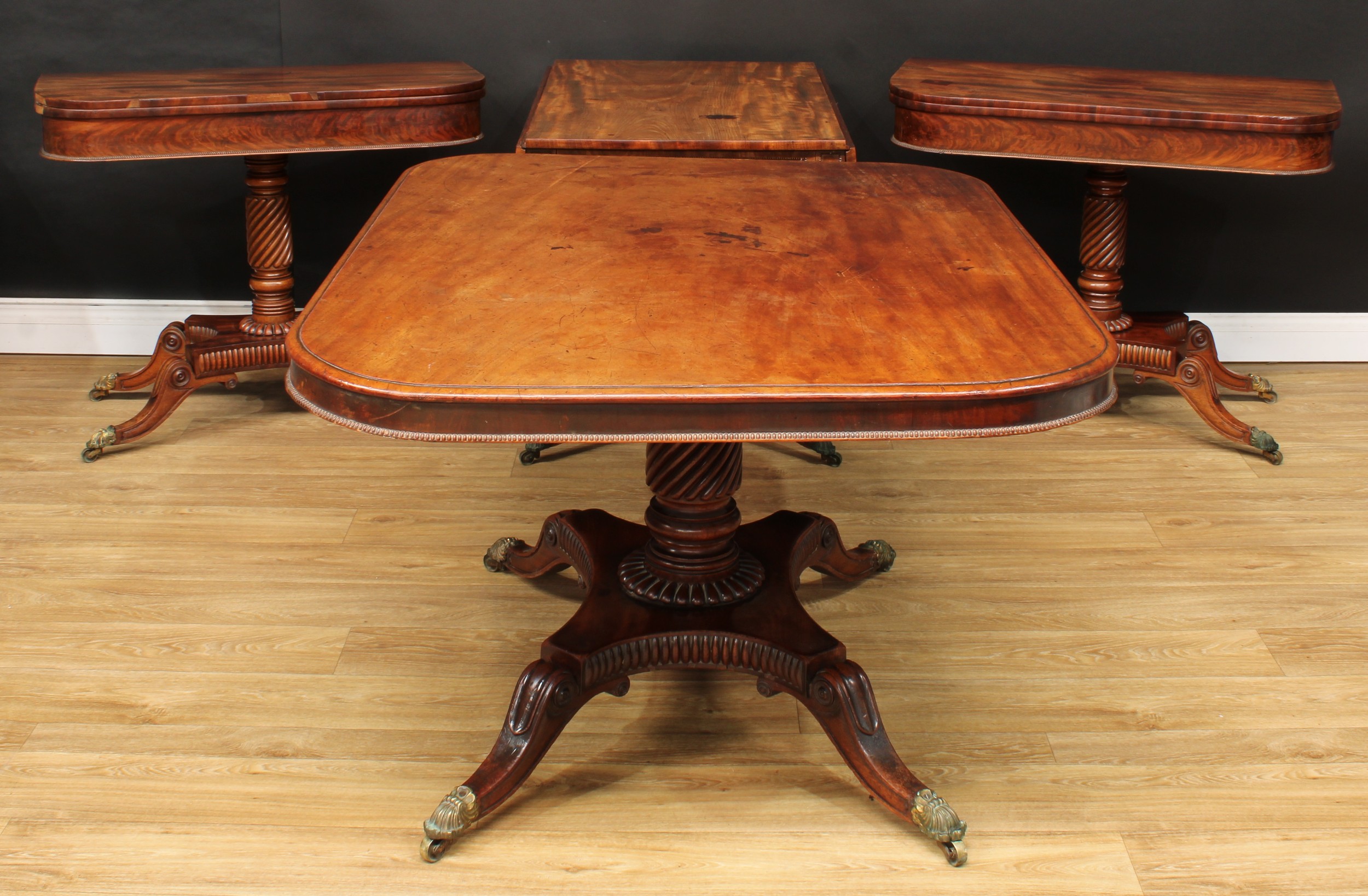 A suite of Regency mahogany drawing room furniture, comprising breakfast table, Pembroke table and a pair of card tables, each with a spirally reeded column, egg-moulded socle, incurve rectangular base, sabre legs applied to the knees with draught-turned roundels, brass capped casters, the breakfast table 71cm high, 133cm long, 99cm wide, the Pembroke table 70cm high, 62.5cm opening to 121.5cm wide, 84cm deep, the card table 73.5cm high, 91.5cm wide, 45cm deep, c.1820