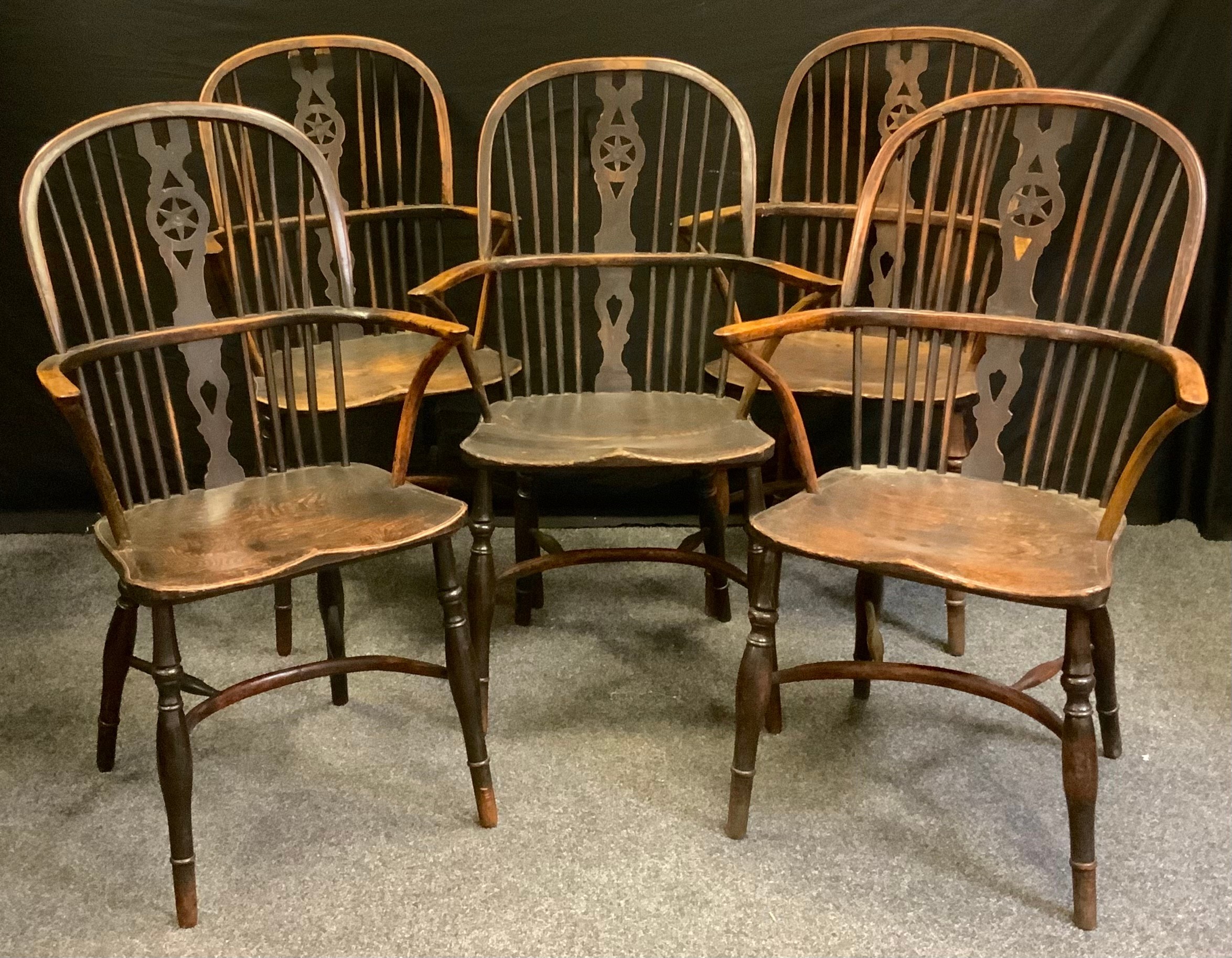 A set of five 19th century country house elm Windsor elbow chairs, hooped backs, shaped and pierced star back splats, saddle seat, turned legs, Crinoline stretcher, 104cm high. (5)