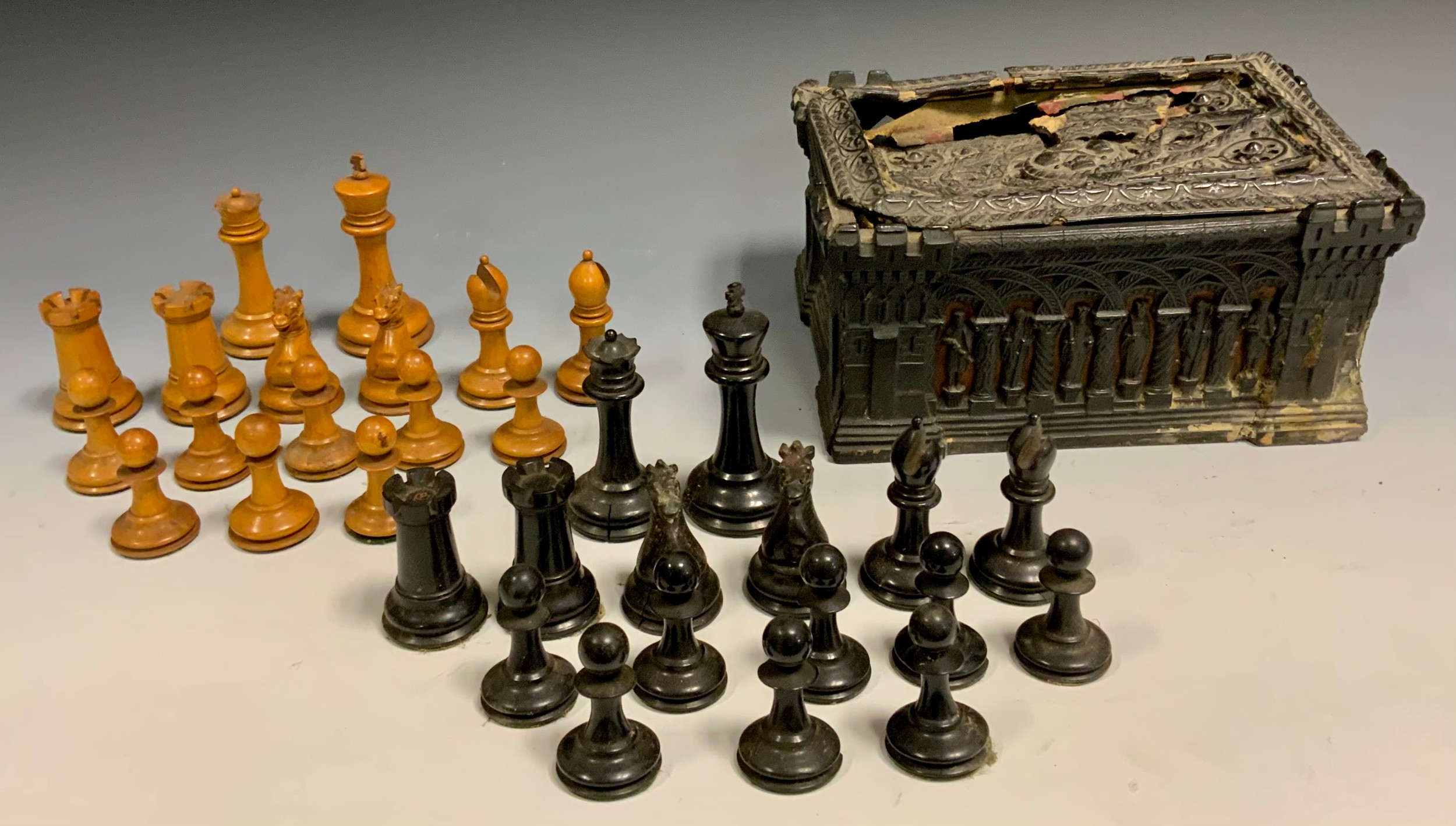A 19th century Jacques boxwood and ebony Staunton pattern chess set, the white king stamped 'Jaques London', 8.5cm high, the king side rooks and knights with crown stamps, all contained in a 19th century Gothic Revival carton-pierre papier-mache casket, with scarlet velvet-lined interior, the base with remains of a Jacques label, 10cm x 21cm x 15.5cm