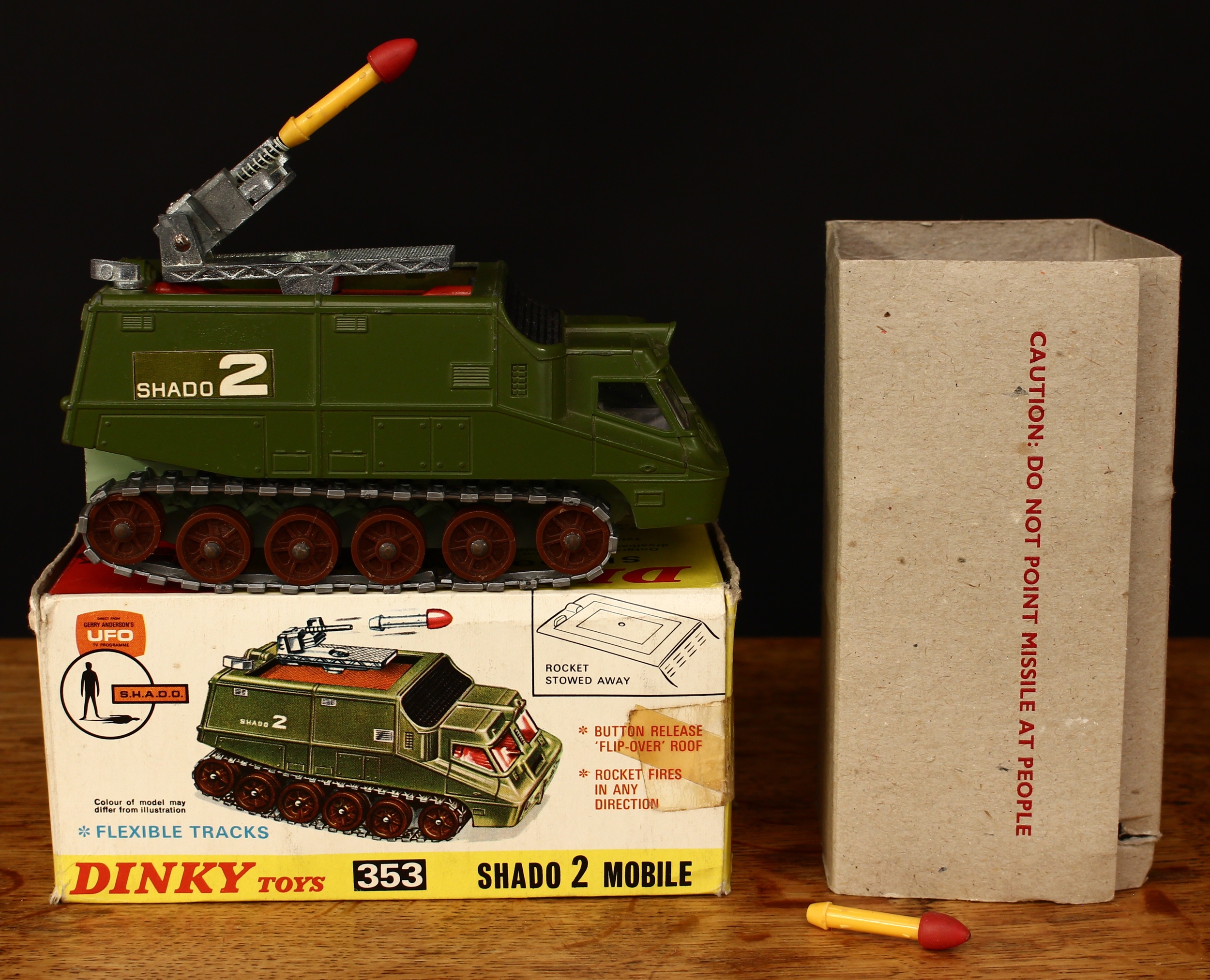 Dinky Toys 353 Shado 2 Mobile from the Gerry Anderson T.V. series U.F.O., green body with 'SHADO 2' rectangular decals to sides, white interior, brown rollers with silver flexible tracks, pale green base, boxed with original inner cardboard packaging piece and two rockets
