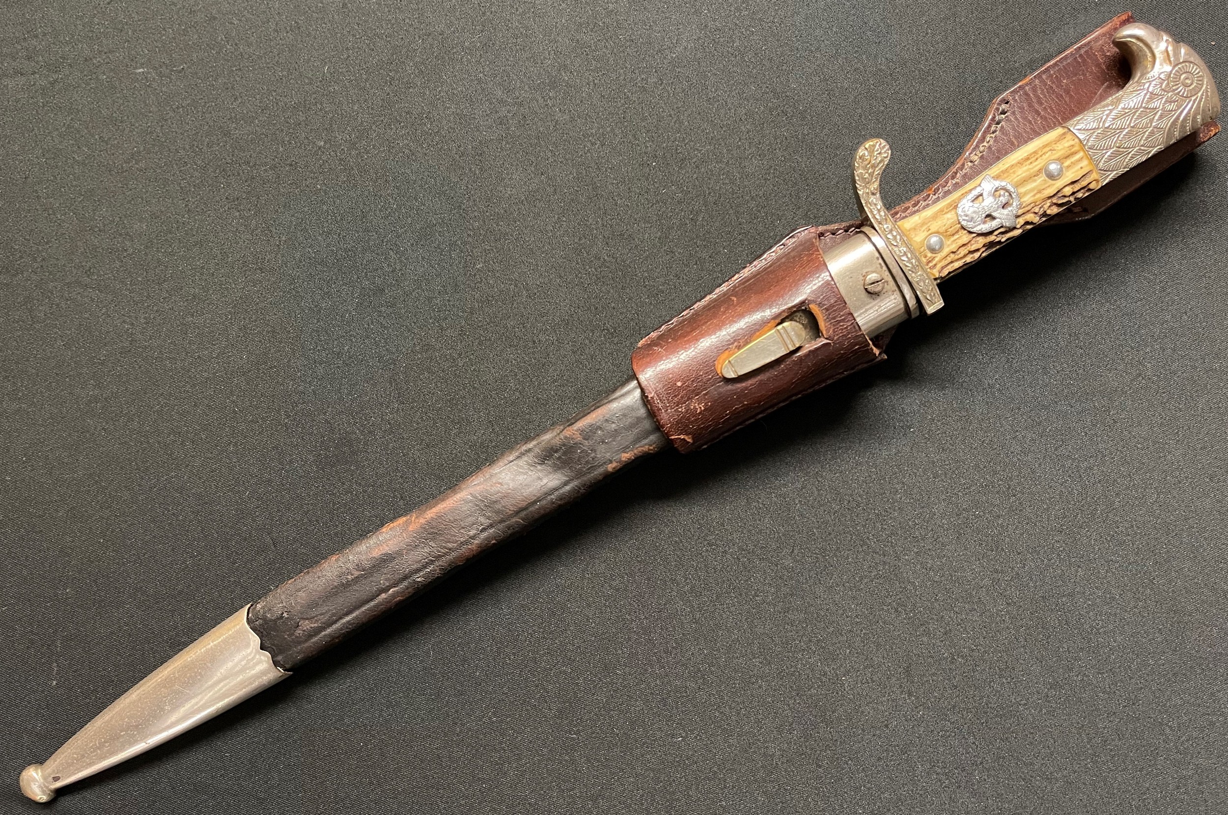 WW2 Third Reich Gendarmerie Police Side Arm. Single edged fullered blade 330mm in length, maker marked "Paul Weyersberg & Co, Solingen". Stag horn grip fitted with Police Eagle. No markings to crossguard. Stylised eagle's head pommel. Overall length 450mm. Complete with brown leather scabbard. Together with brown Police leather frog