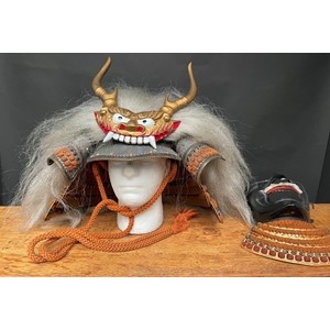 Japanese Samurai Warriors Kabuto Helmet, Faceplate, Greaves shin armour, brown fur shoes plus a black wooden slot together Sword stand, all contained in a black lacquered box with decorative brass mounts. Size width 65cm, height 57cm, depth 47cm.