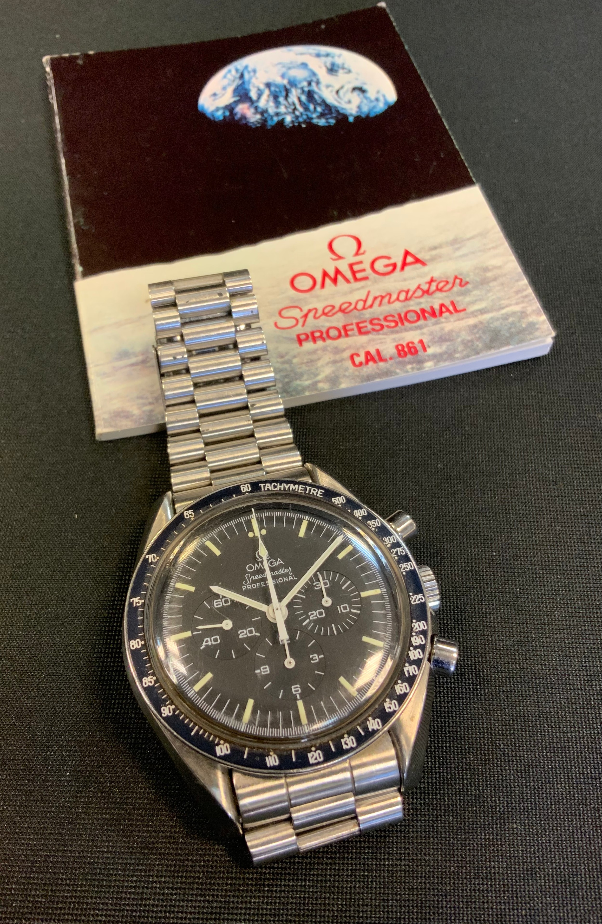 An Omega Speedmaster Professional  APOLLO XI Moon Landings wristwatch Circa 1989, stainless steel case marked Omega Speedmaster - First Watch Worn On The Moon, Apollo XI,  pump push button and no-screw type crown. Matte black dial, luminous bâton indexes, outer minute/seconds divisions, subsidiary dials for  0-60 seconds, 0-30 minute and 12-hours registers. white luminescent bâton hands and arrow markers, manual winding cal 863 movement, signed “Omega 17 jewel”, serial No 48169783, steel case with fixed black bezel, graduated tachymeter scale up to 500 units, screwed window back case, Omega stainless steel link bracelet No.1447, with deployment clasp, four spare links, instruction book, original guarantee booklet dated 28th July 1989, purchase receipt and service paperwork.