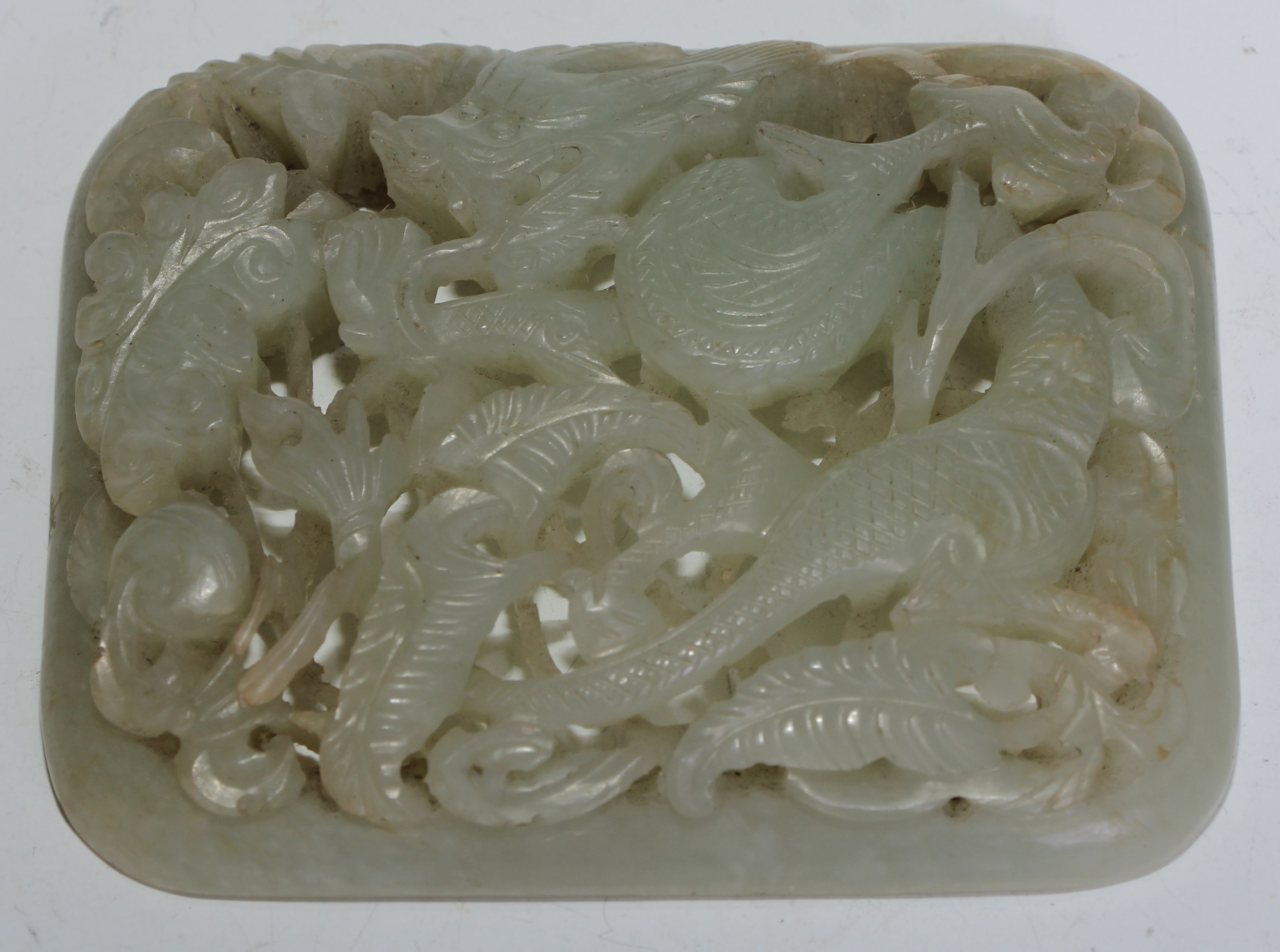A Chinese pale celadon nephrite panel, carved and pierced with a styalised bird amongst leafy stems, late Qing dynasty, 7.5cm wide, 6cm high.