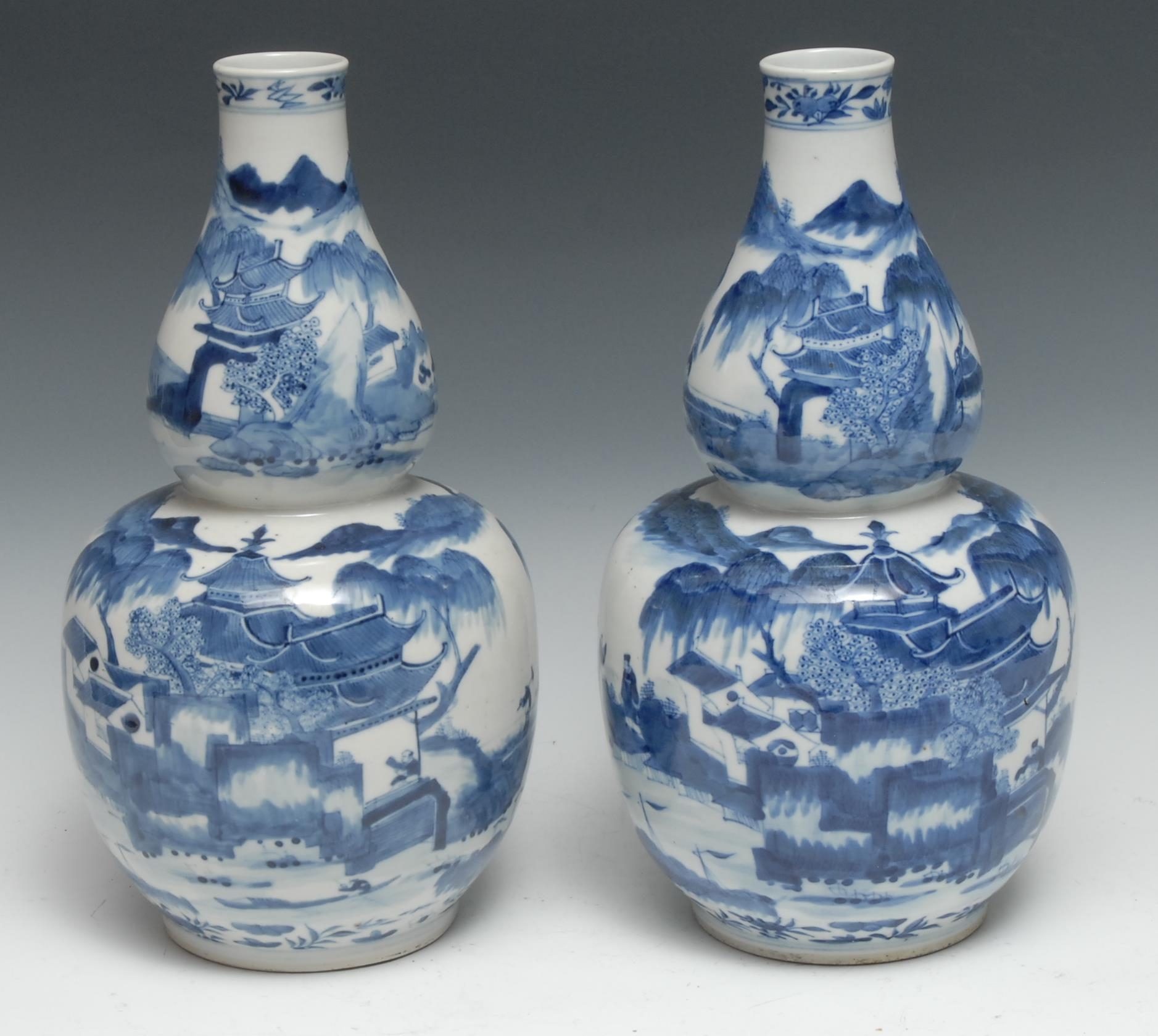 A pair of Chinese  double gourd vases, decorated in underglaze blue with pagodas and figures, 32.5cm high, four character mark, Kangxi mark