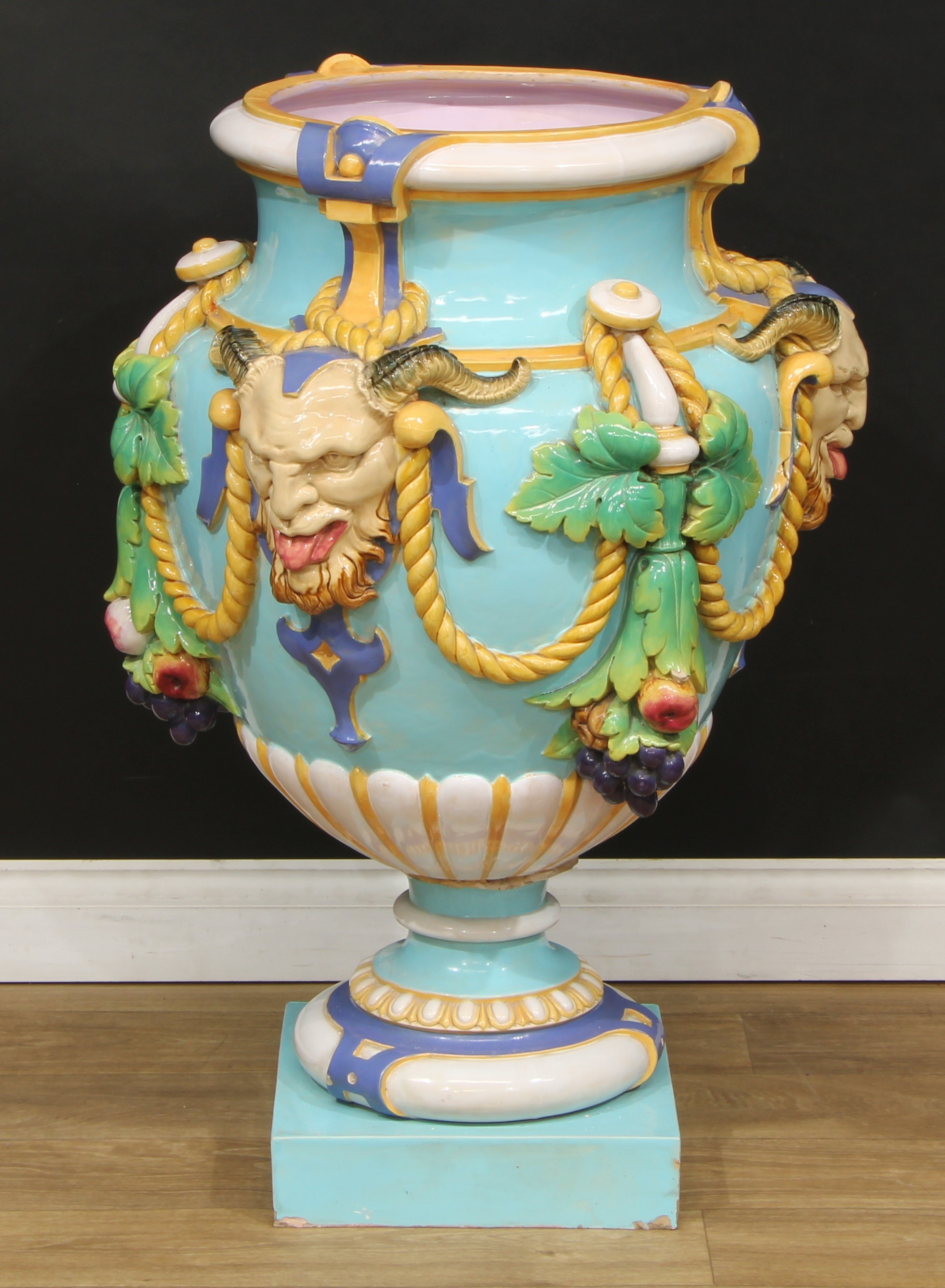 A large Minton Majolica pedestal ovoid vase, in relief with garlands of of fruit and foliage, suspended from satyr masks on a turquoise ground, 94.5cm high, impressed marks, c.1880