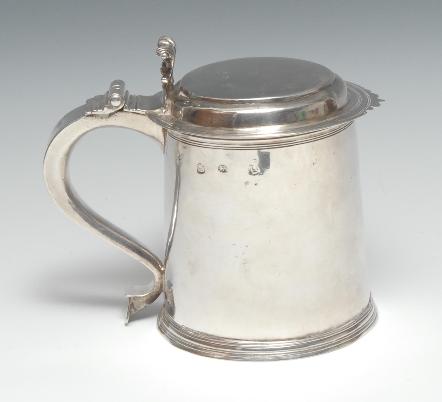 A William & Mary silver cylindrical tankard, hinged flat-top cover with volute thumbpiece, S-scroll handle, skirted base, 16cm high, maker RG with mullet above?, London 1690, 612g