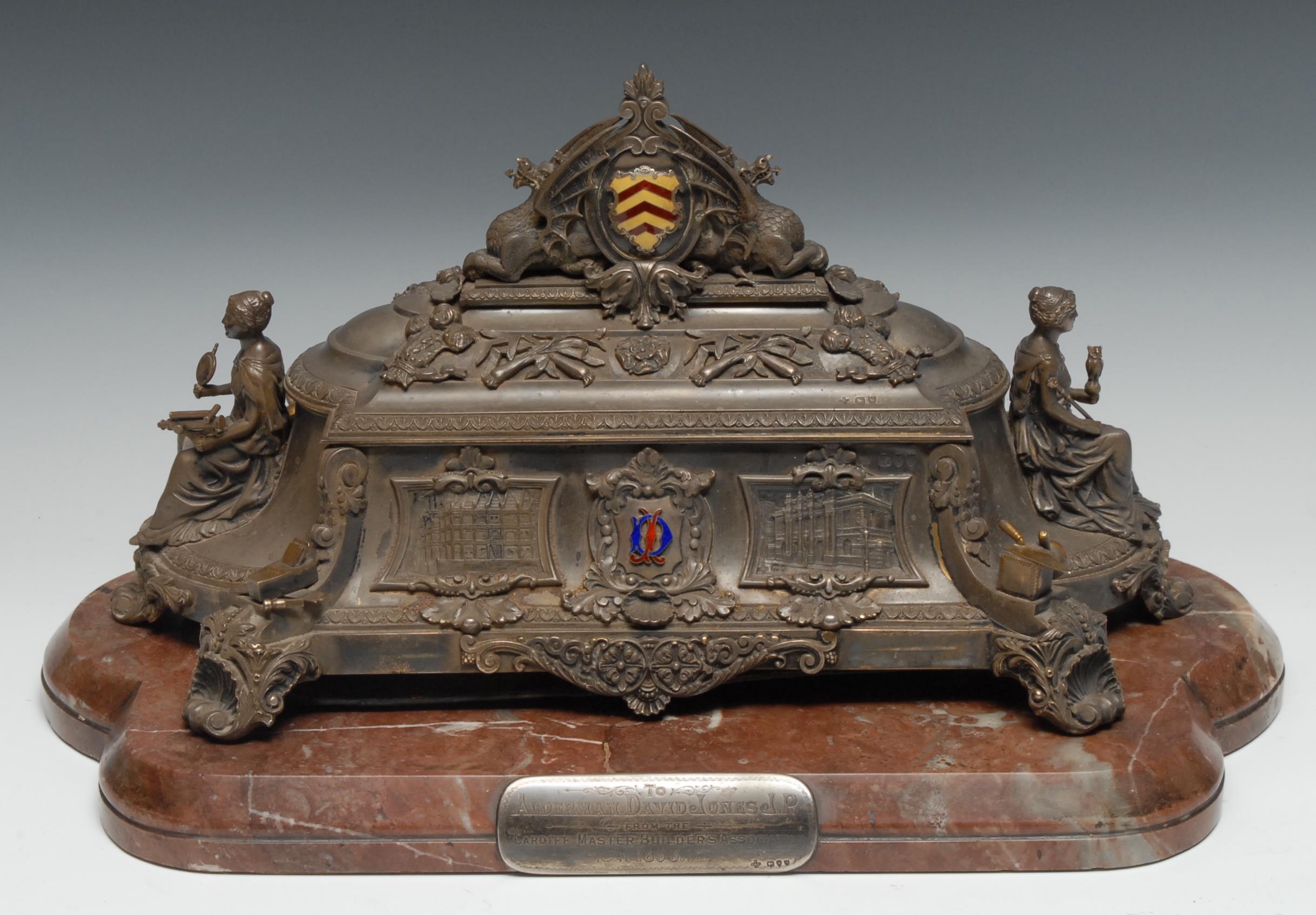 A sculptural Victorian silver, silver-gilt and enamel freedom casket, of Welsh interest, hinged cover crested by the coat of arms of the City of Cardiff supported by dragons. profusely decorated with figures and attributes, architectural views, leeks, Prince of Wales Feathers and further national and allegorical emblems, the angles with masonic tools, 42cm wide, retailed by Barry & Sons, Cardiff,  Horace Woodward & Co Ltd, London 1893, the substantial marble plinth 49cm wide, hand-scrivened presentation address en suite  Provenance: Presented to Alderman David Jones JP, President of the Cardiff Master Builders Association thence by descent