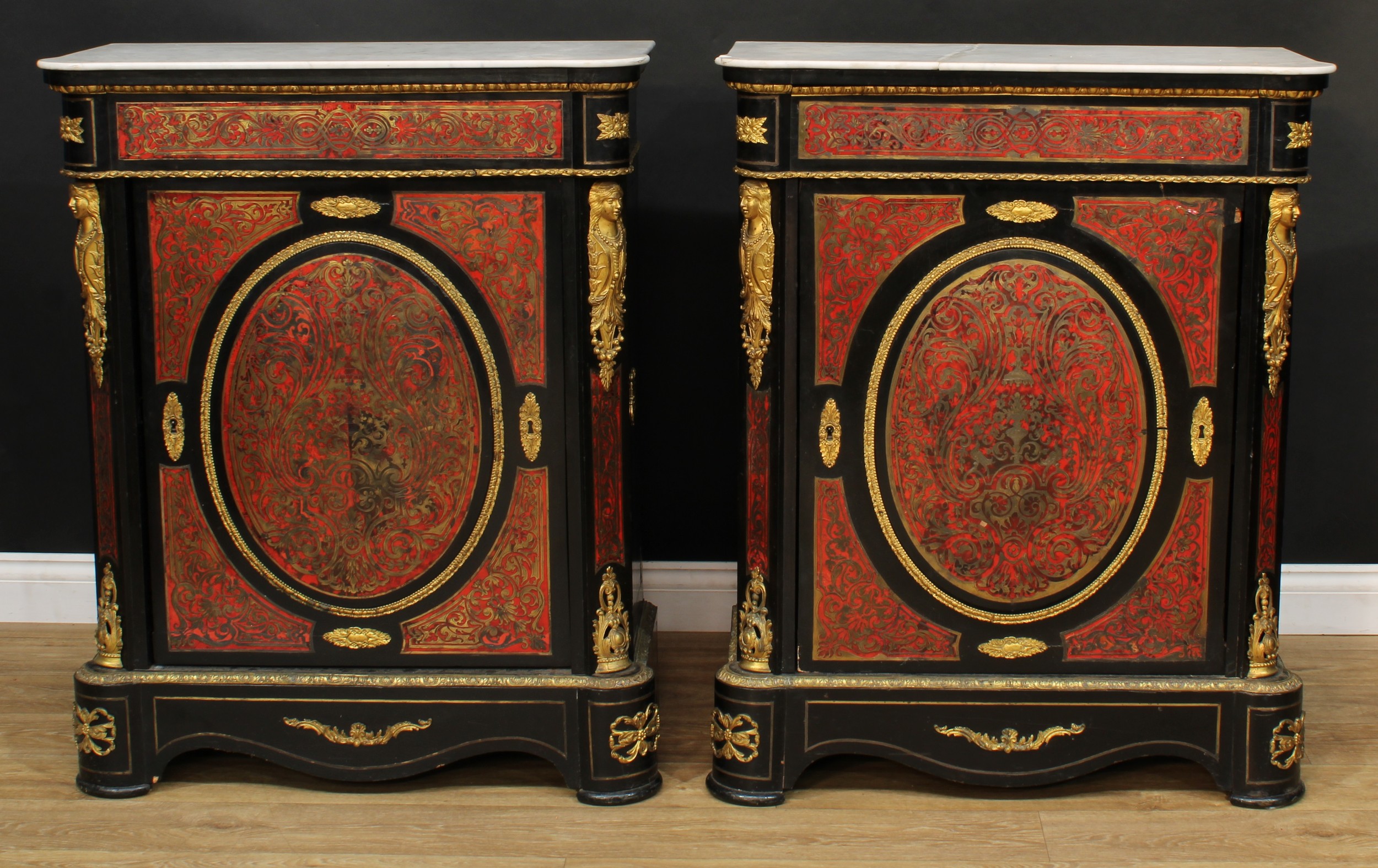A pair of 19th century gilt metal mounted Boulle and ebonised pier cabinets, each with a hipped rectangular marble top above a rectangular door, flanked by female herm brackets, shaped plinth base, 103.5cm high, 84cm wide, 40.5cm deep, c.1870