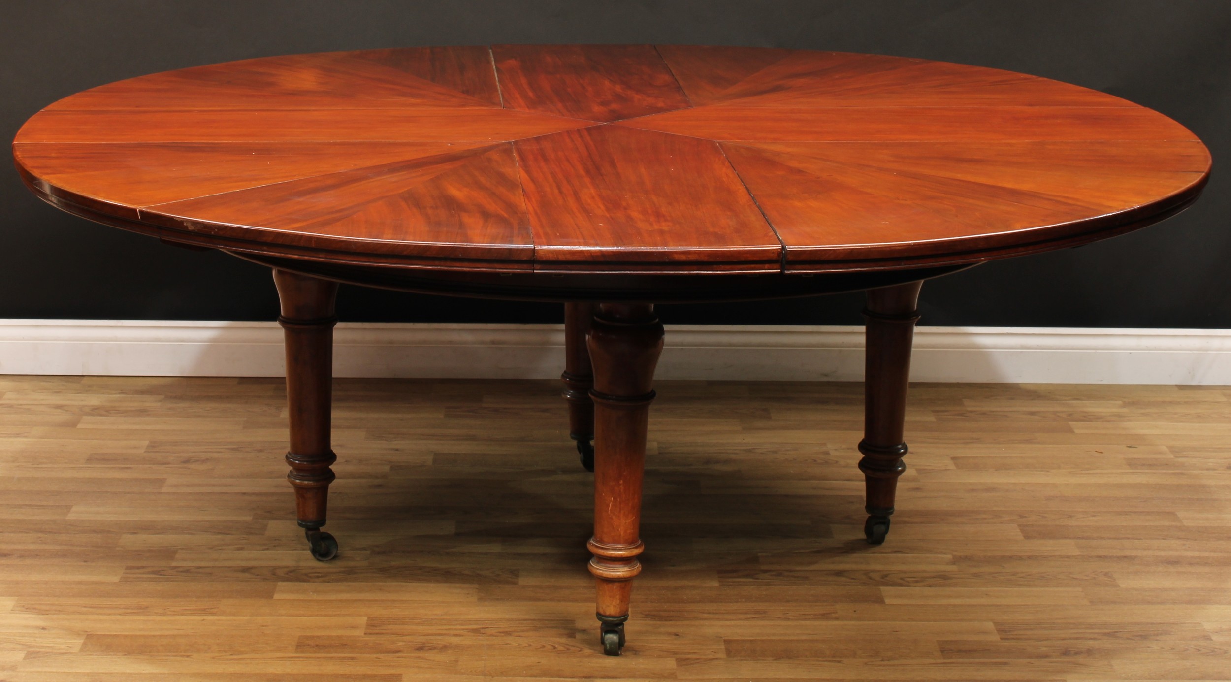 A 19th century mahogany Jupe's patent type radial extending dining table, in the manner of Jupe, Johnstone & Jeanes, circular top in four segments, sliding to accomodate four small or four large additional leaves, turned legs, brass casters, 76cm high, 159cm extending to either 175cm or 192cm diameter