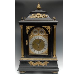 A substantial Victorian gilt-metal mounted ebonised repeating musical bracket clock, in the George II taste, 20cm arched brass dial with silvered chapter ring, inscribed with Roman and subsidiary Arabic numerals, Chime/Silent and Chime on 8 Bells/Westminster setting dials to arch, three-train movement striking on a gong, the caddy-top case with pine cone finials, flanked by a pair of Corinthian columns, fluted bun feet, 71cm high, c. 1880