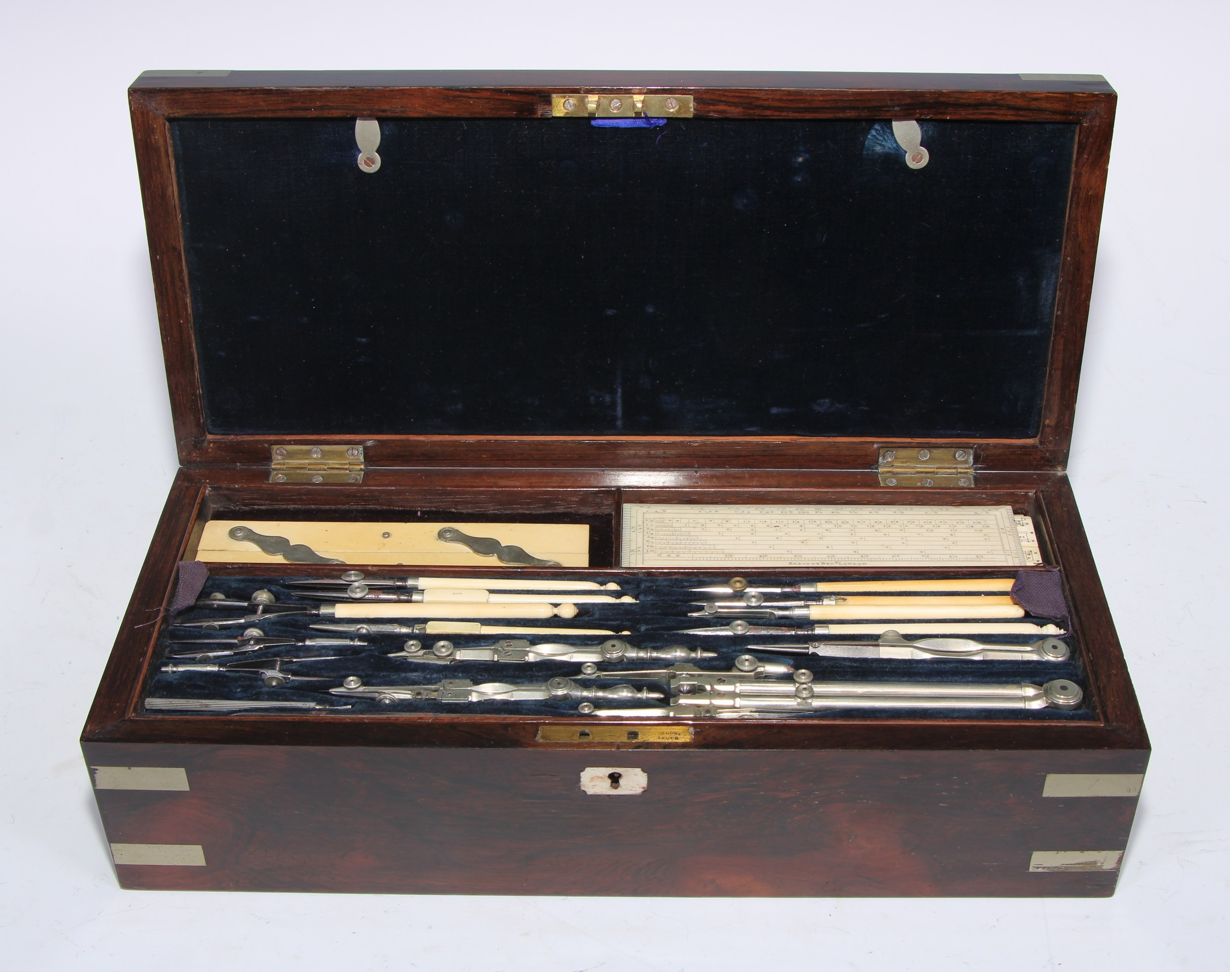 A large Victorian rosewood draughtsman's box, hinged cover enclosing a fitted interior with a comprehensive arrangement of techinical drawing instruments, including a protractor by Baker, 244 High Holborn, London, plated campaign type mounts, 36cm wide, c.1870