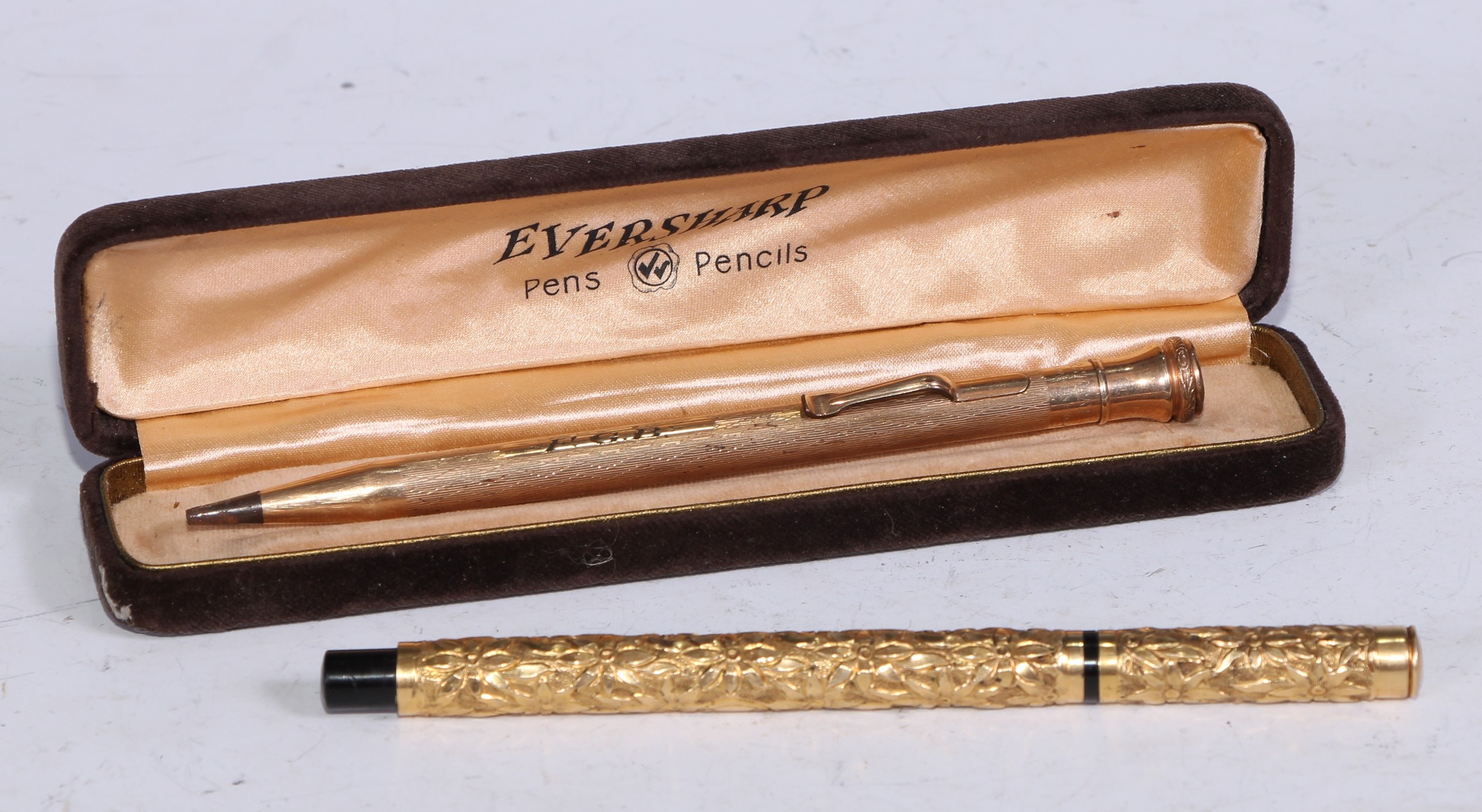 Pens - an early 20th century gold coloured metal mounted fountain pen, by Aikin Lambert & Co, profusely chased with flowers on a textured ground, 13.5cm long; an Eversharp rolled gold propelling pencil (2)