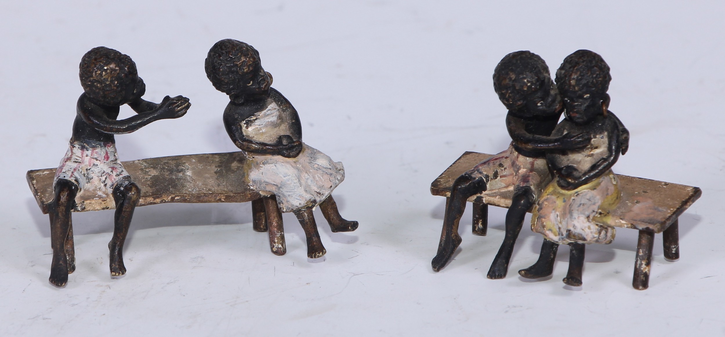 A pair of Austrian cold painted bronzes, of a young black boy and his reluctant sweetheart, seated on a bench, 6cm and 4.5cm wide, Vienna, c.1900