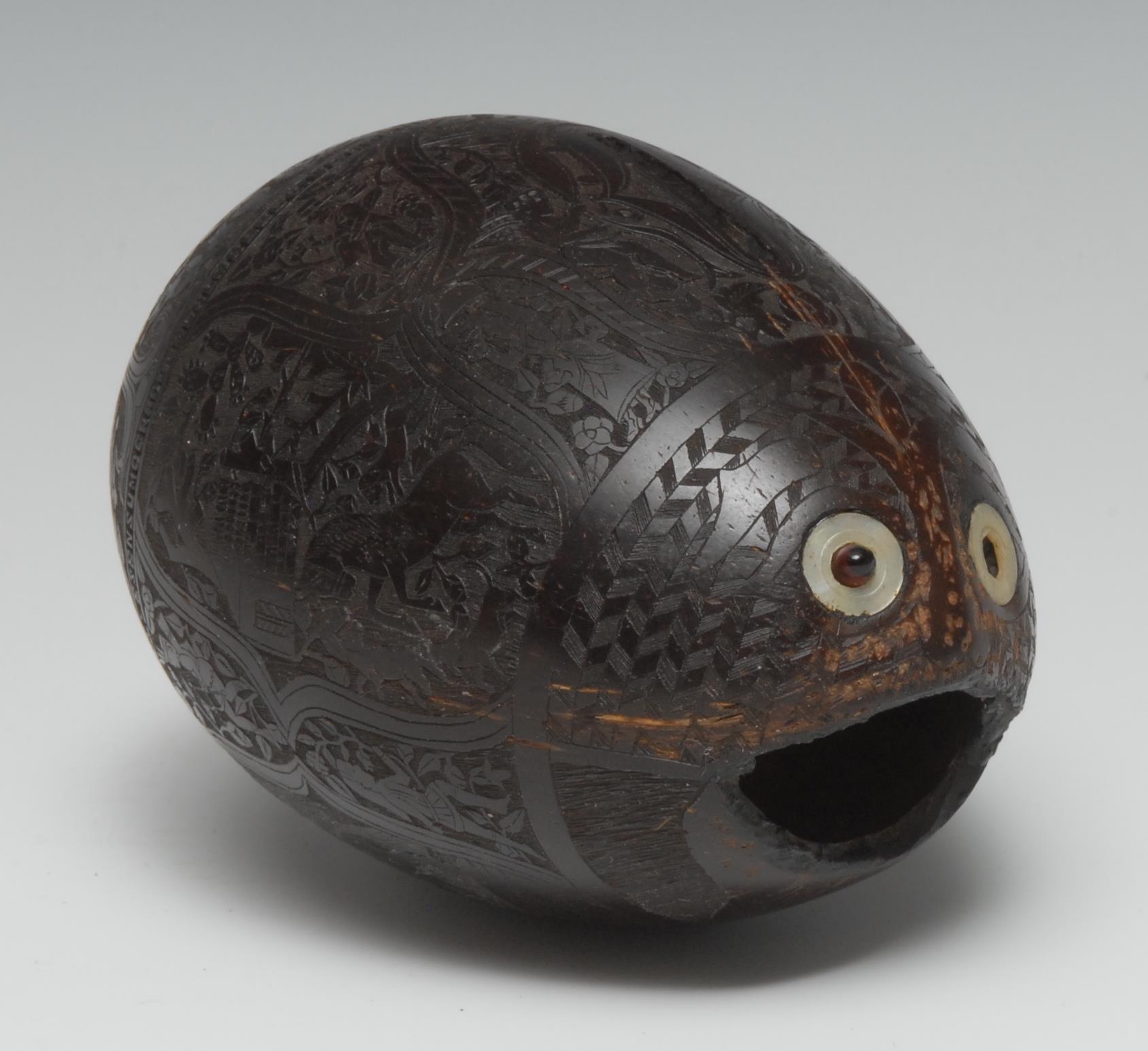 Treen - a 19th century Mexican coconut bugbear money box, profusely carved with figures, emblems and patriotic verse (translating as Honour is Commended to the Soul of the Citizen... Without Honour...Vain or Pernicious member of the State), inlaid mother of pearl eyes, 13cm long