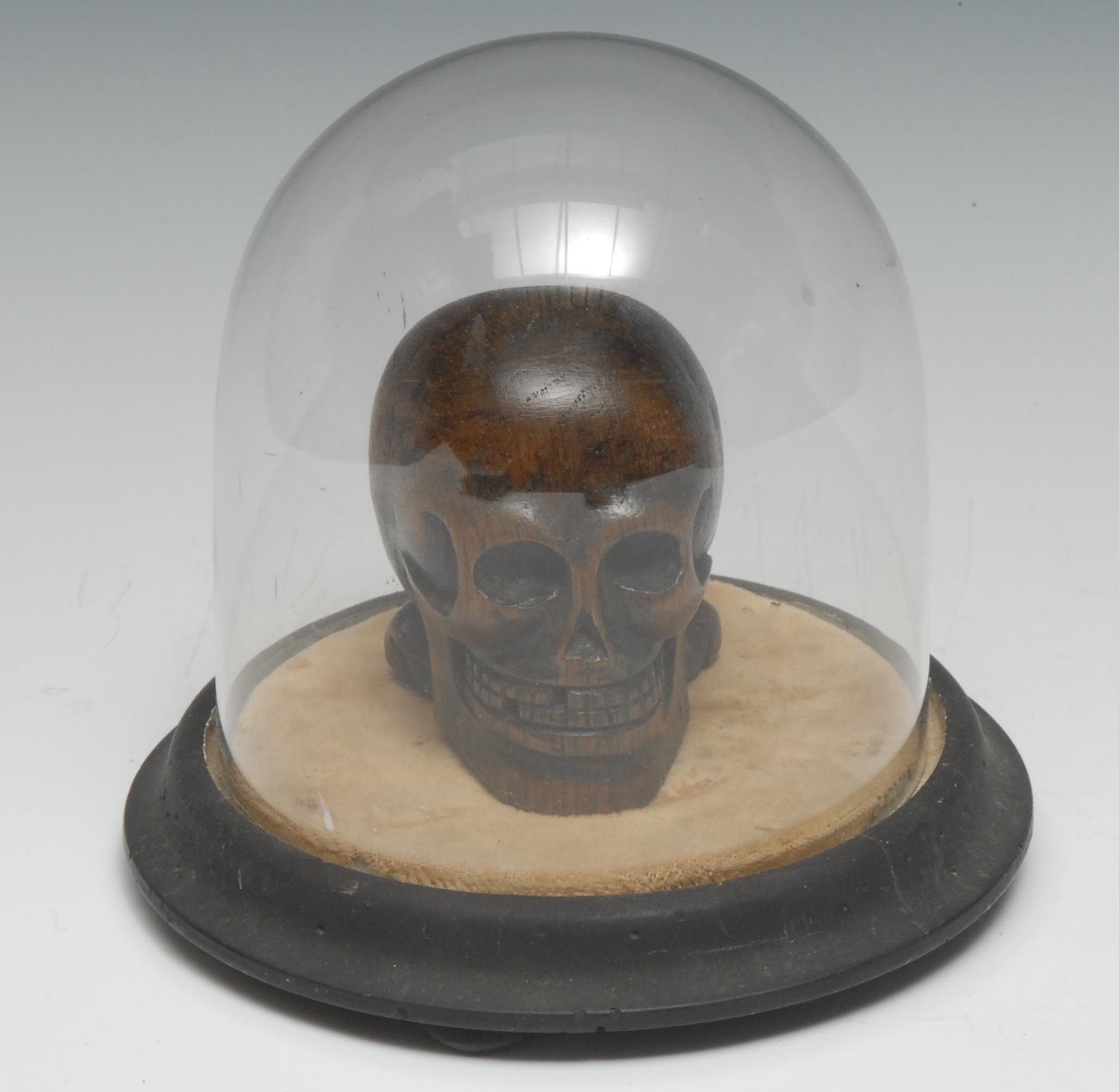 The Macabre - a 19th century oak memento mori, carved as a skull, glass dome with ebonised base, bun feet, 16cm high