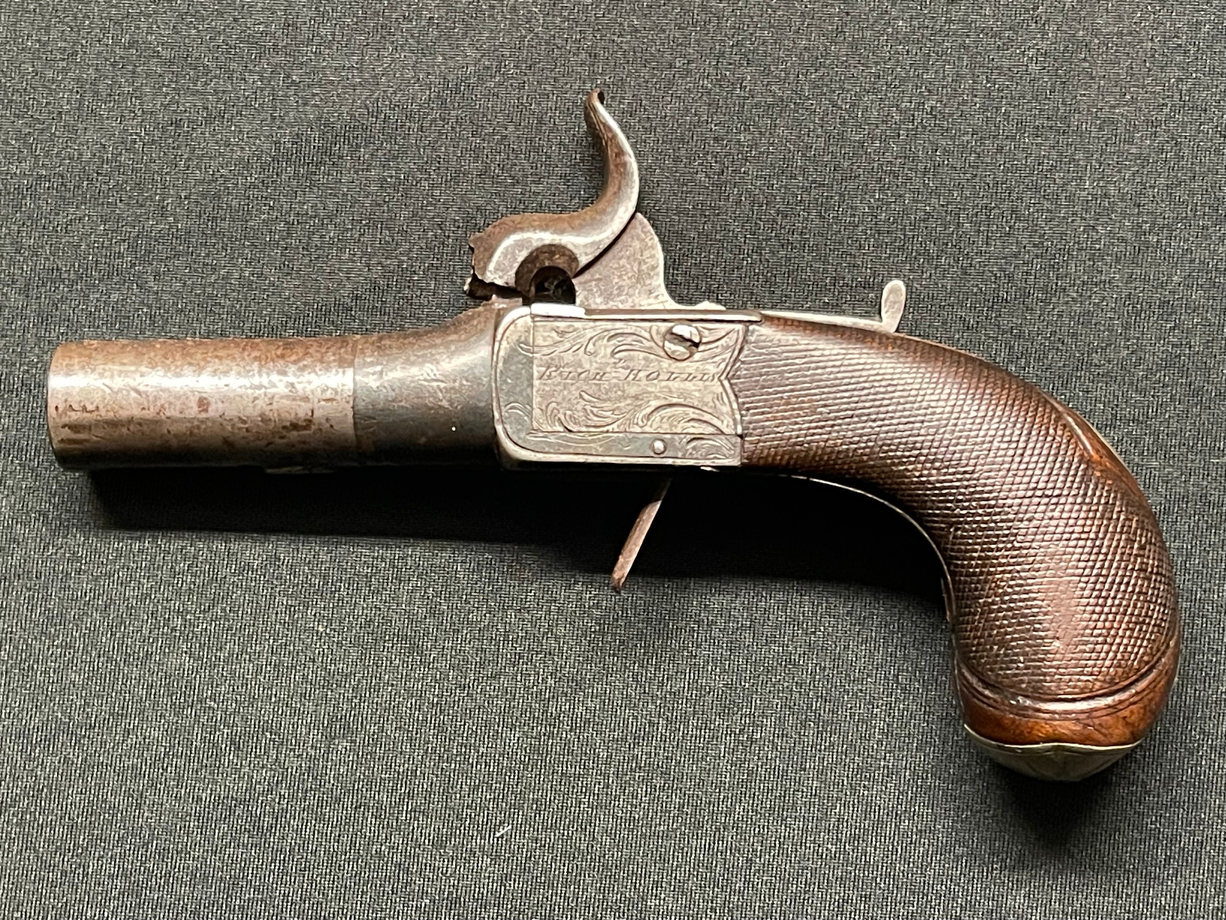 Percussion cap pocket pistol with 55mm long barrel. Bore approx. 11mm. Lock is signed "Rich. Hollis" along with "London". Blank Silver escutcheon plate along with silver mounts to checkered butt. Working action. Folding trigger. Safety catch. Overall length 147mm. Section 58 (2) no licence required.