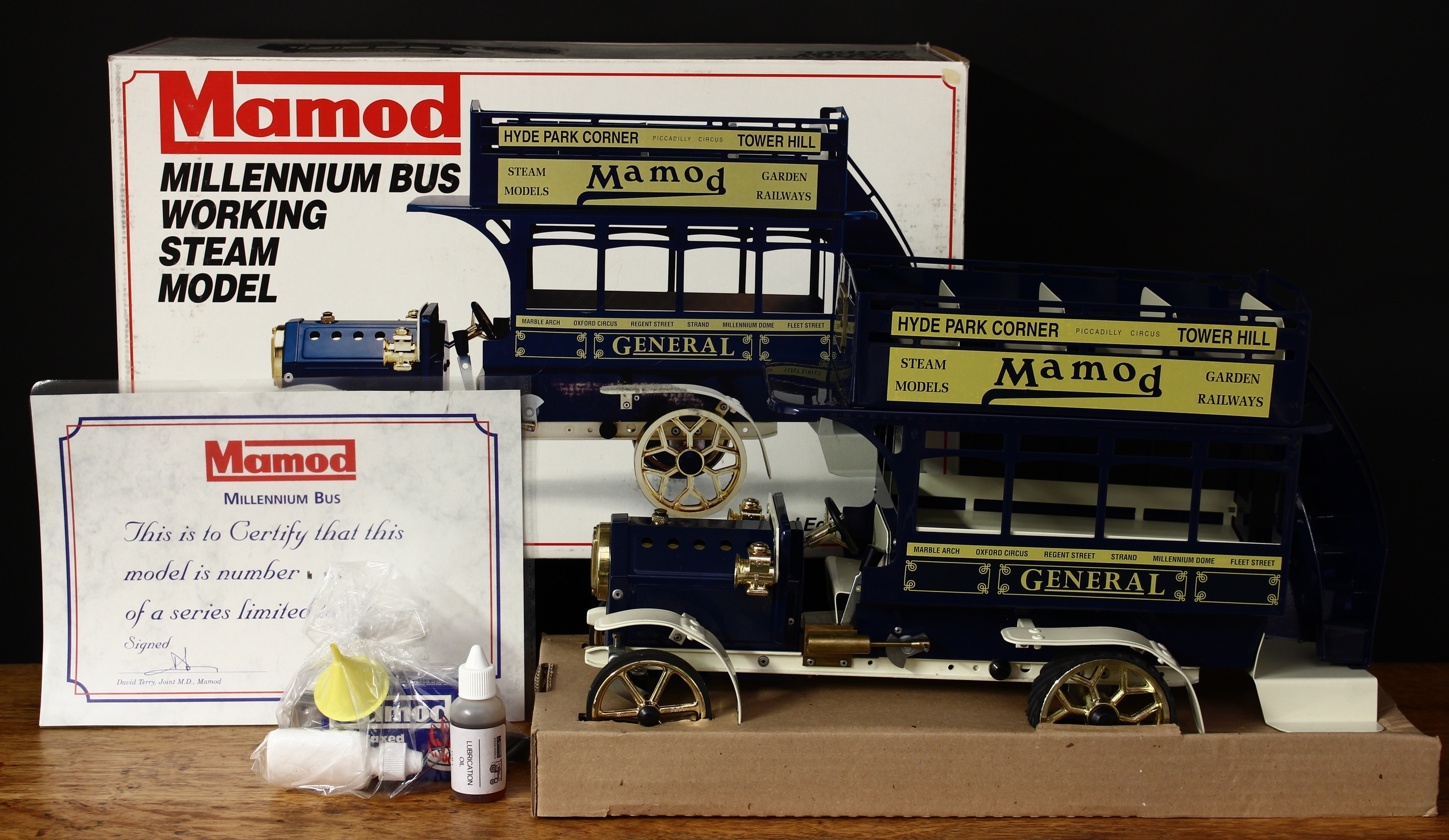 A Mamod M.B.1 live steam Millennium bus, navy blue body with cream chassis, wheel arches and seats, gold spoked wheels, fitted with a safety valve and filler, boxed with original inner cardboard packaging pieces, two bottles of LUB1 lubrication oil, yellow plastic funnel, a box of 20 waxed solid fuel tablets, burner tray and certificate, Limited Edition No.154 of 250