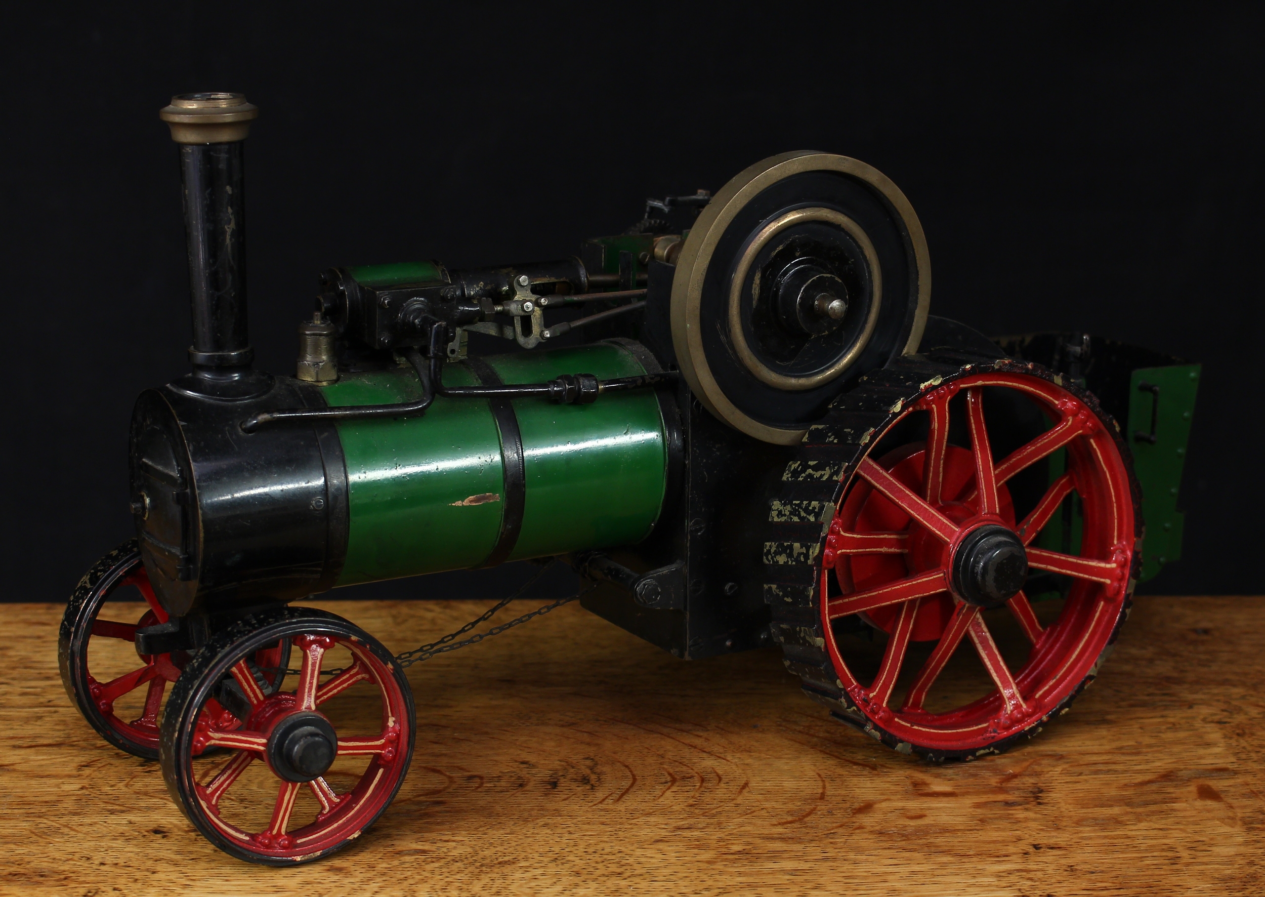 A live steam model traction engine, green livery, fitted with English style brass straked wheels, 3.5” solid cast brass flywheel, single chimney, 40cm long