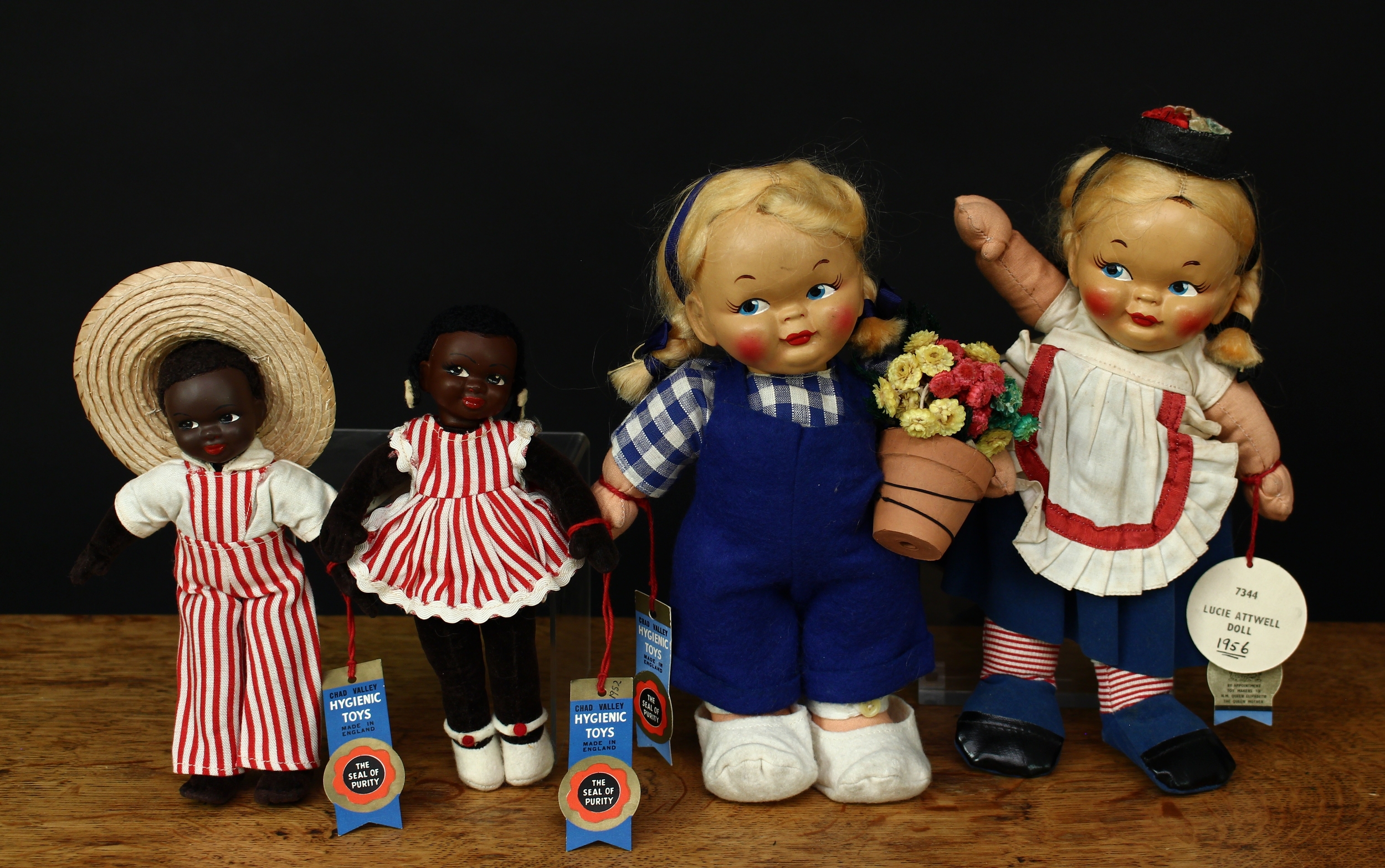 A Chad Valley ‘Hygienic Toys’ No.7344 Mabel Lucie Attwell doll, painted composition head, painted features including blue side glancing eyes, stuffed cloth body, 24cm high with tags; another Mabel Lucie Attwell doll, 23cm high with tag; a pair of Chad Valley ‘Hygienic Toys’ black dolls, modelled as a boy and girl, each with painted composition heads and stuffed velveteen bodies, each wearing red and white pinstripe outfits, each 18cm high with tags (4)
