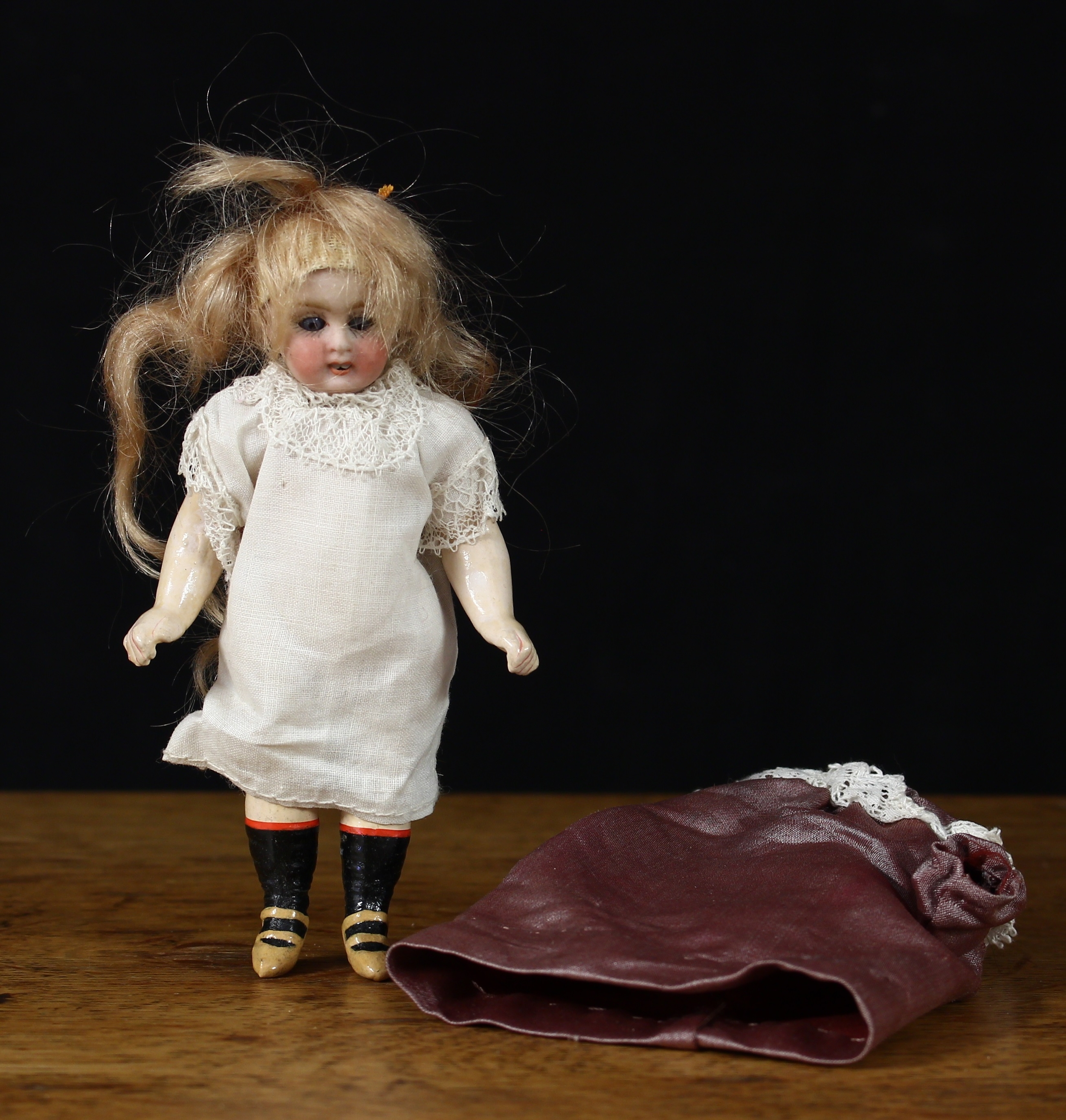 A bisque head and painted composition miniature doll, weighted sleeping blue glass eyes, painted features including fine eyelashes and brown eyebrows, open mouth revealing teeth, blonde wig, 11cm high