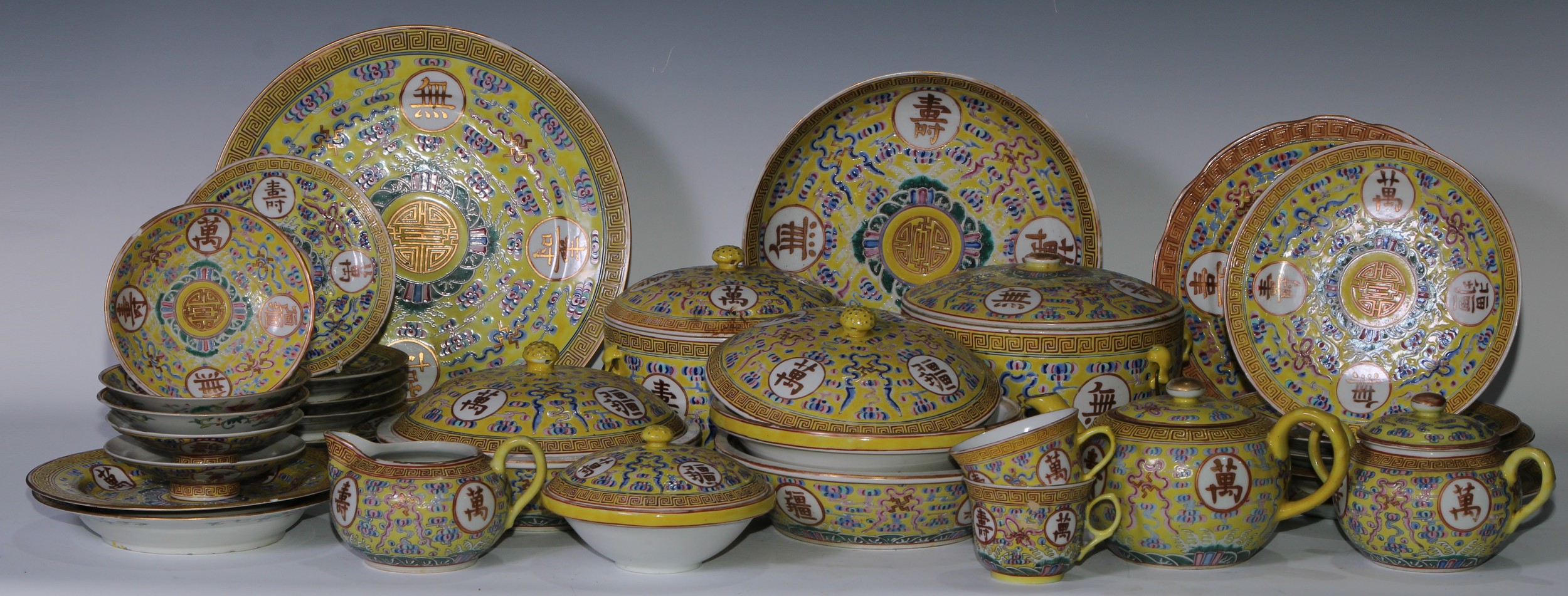 A Chinese dinner and tea service, comprising teapot, milk jug, cups, saucers, tureens , plates and dishes, each decorated in polychrome enamels with auspicious symbols, scrolling cloud and trellis, picked out in gilt on a yellow ground, the largest plate 28cm diam, Guangxu mark and of the period, c.1875 - 1908 (qty)
