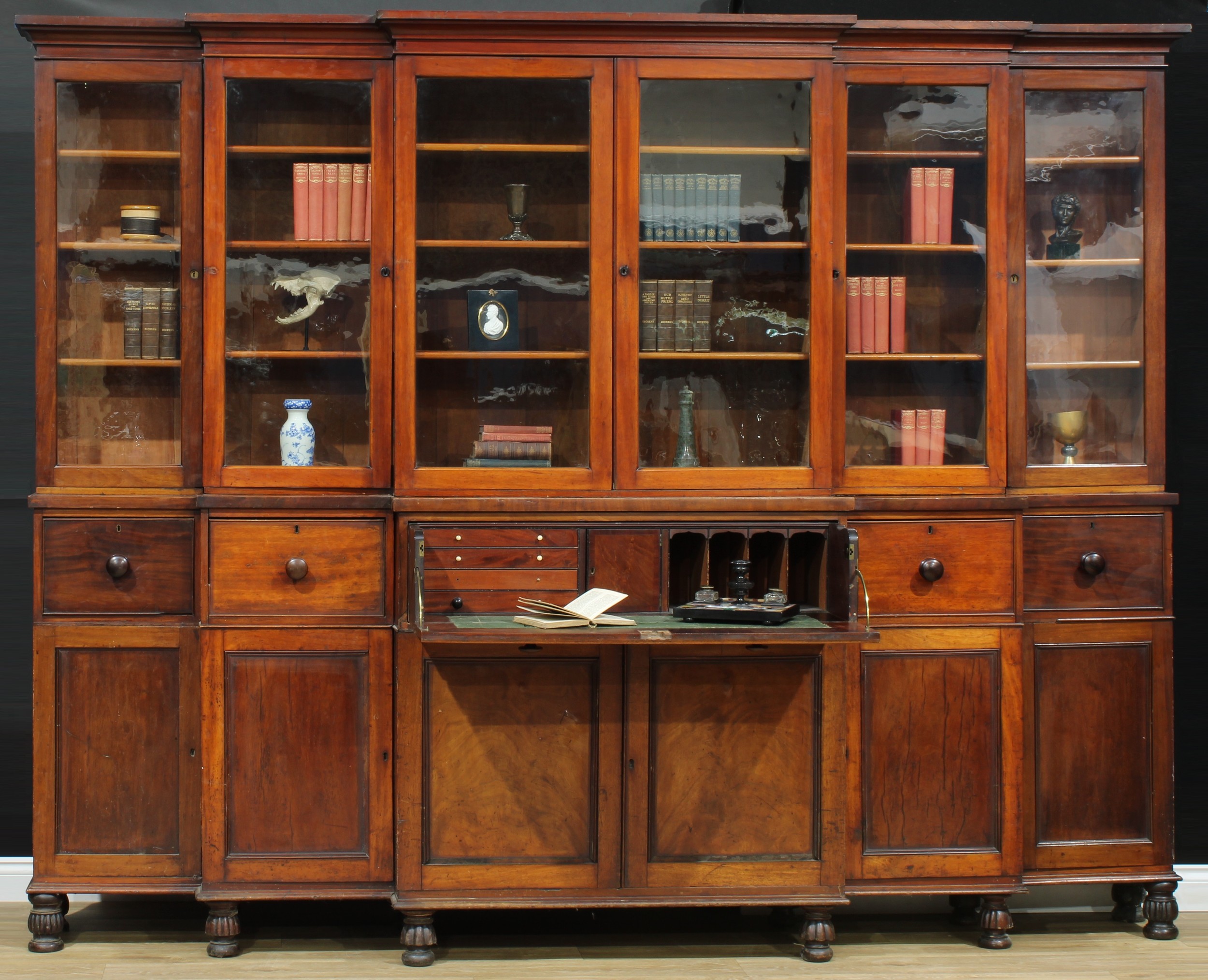 A substantial early Victorian mahogany stepped breakfront library secretaire bookcase, outswept cornice above six glazed rectangular doors, the projecting base with fitted drawer above a pair of rectangular panel doors flanked by four further drawers and cupboards, turned and fluted feet, 227cm high, 282cm wide, 52.5cm deep, c.1840