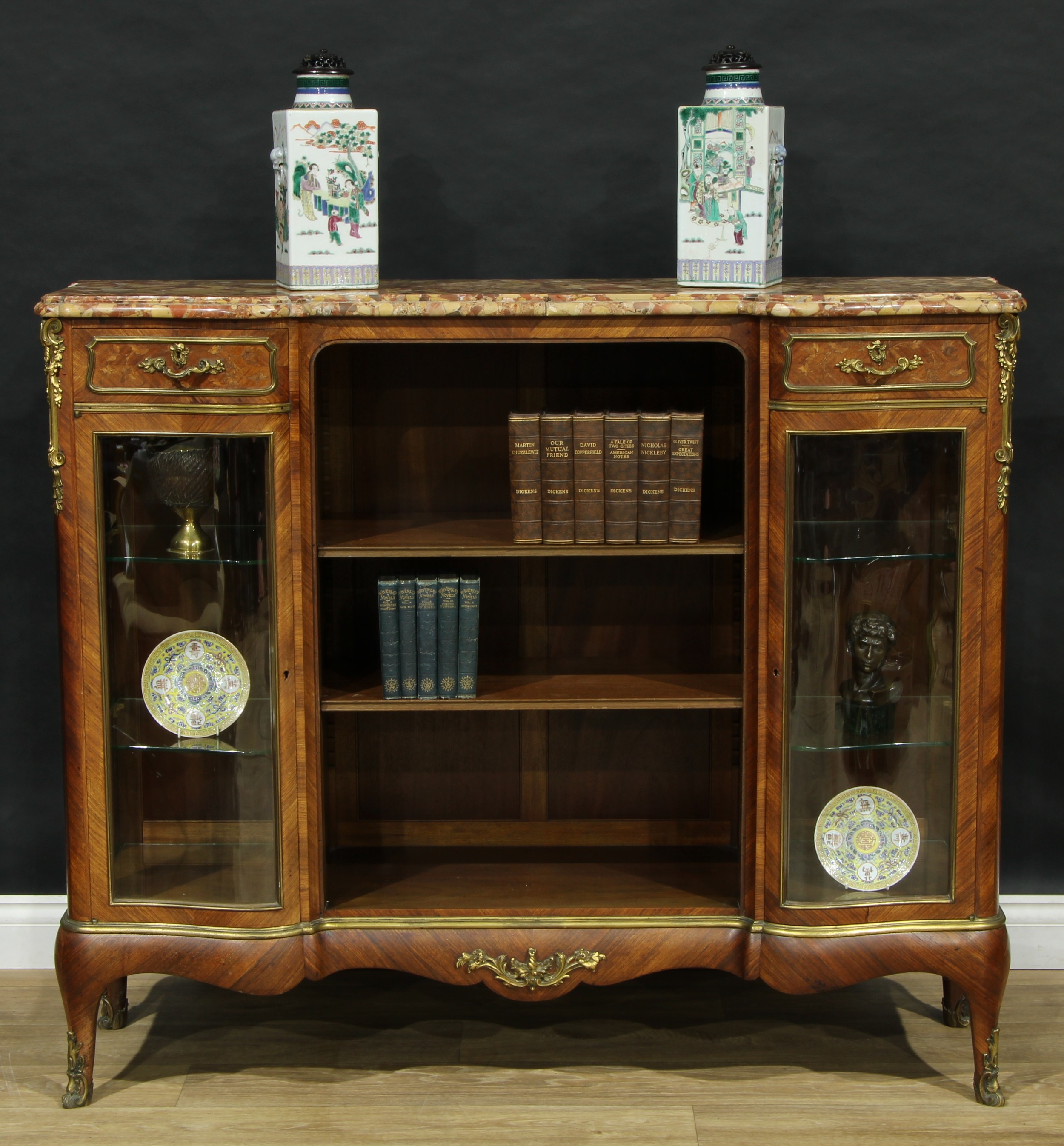 A 19th century Franglais gilt metal mounted kingwood and marquetry library side cabinet, marble top above a bookcase centre with adjustable shelves, flanked by small drawers and serpentine vitrine cabinets, cabriole legs, 113cm high, 134cm wide, 42cm deep, c.1890