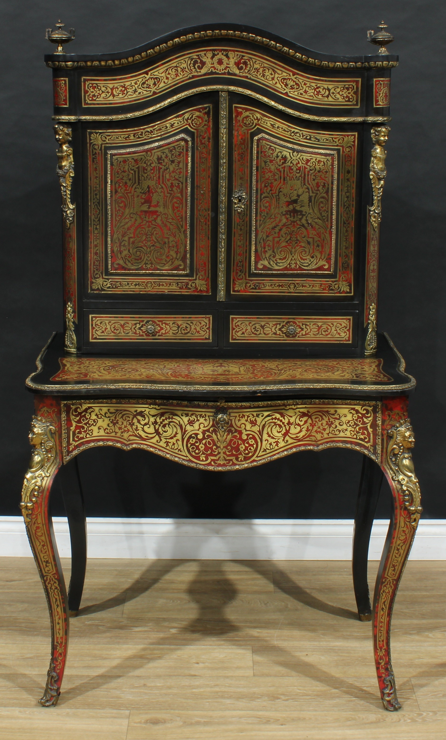 A 19th century gilt metal mounted Boulle and ebonised bonheur du jour, serpentine cresting flanked by urnular finials, above a pair of panel doors and small drawers, the projecting base with slide and drawer to frieze, serpentine legs, 150cm high, 83cm wide, 58cm deep, c.1860