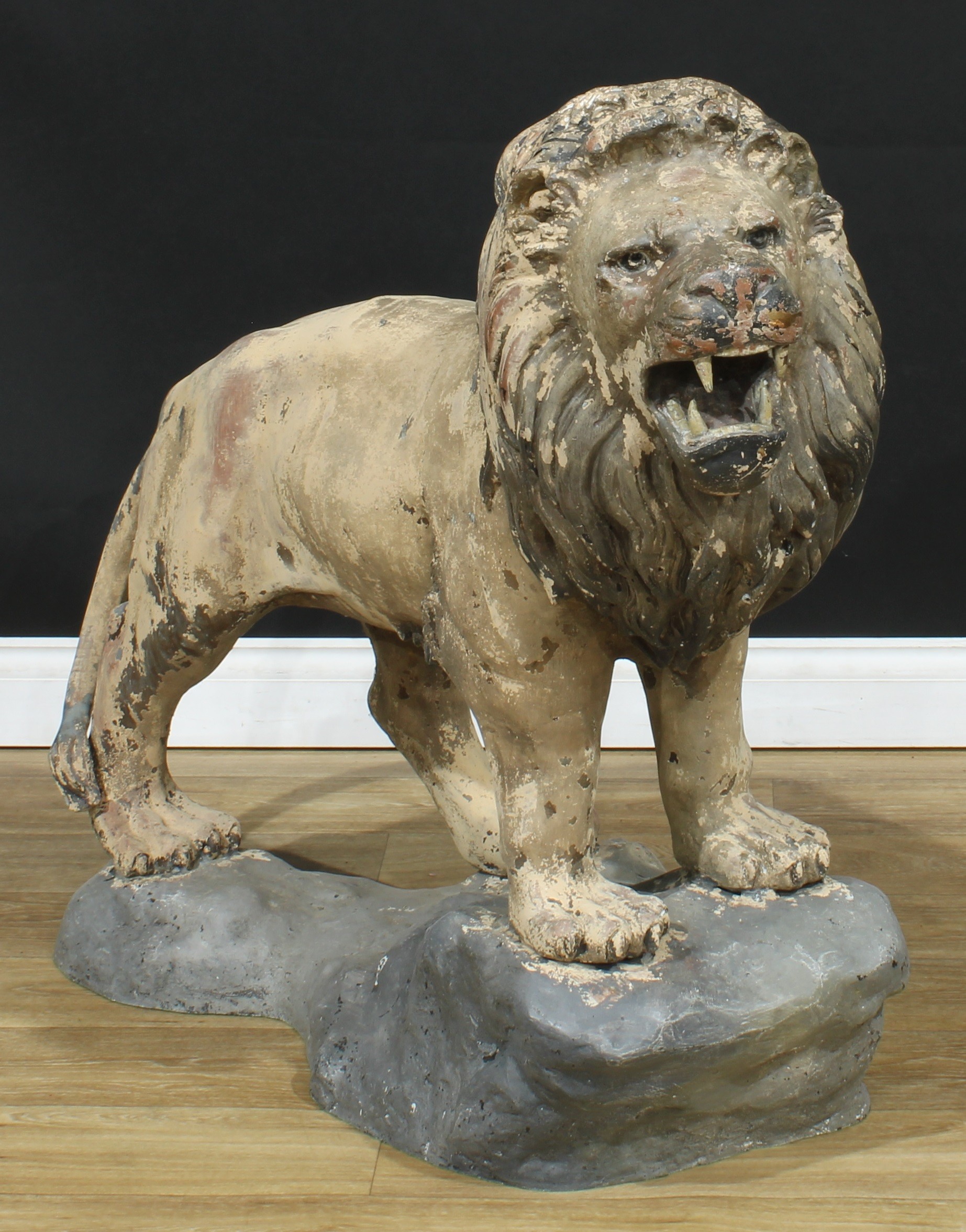 A substantial floor-standing cold painted bronze, of a snarling lion, standing on a rocky outcrop, 91.5cm high, 112cm long