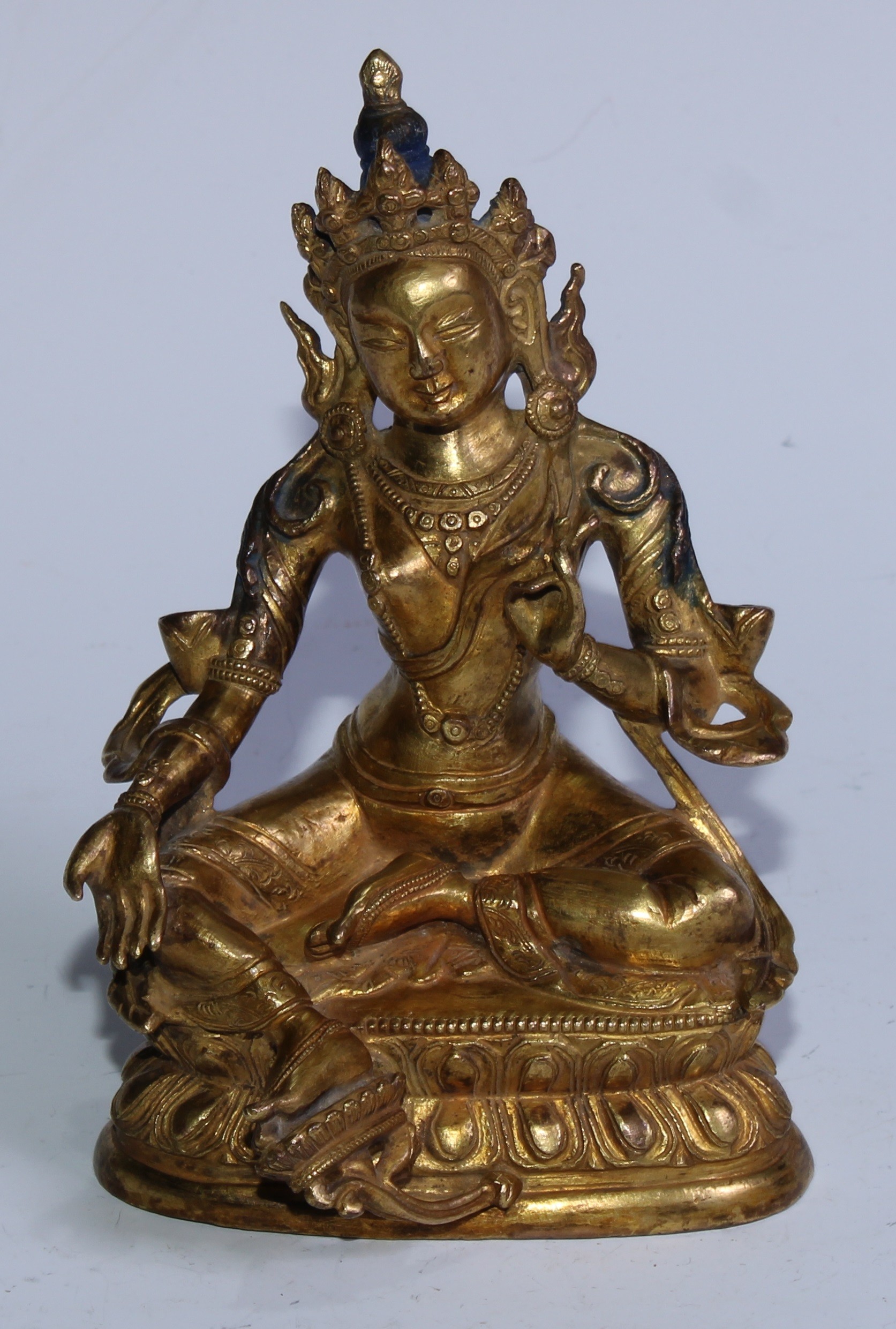 A 19th century gilt bronze Tara Buddha, typically seated with her right foot resting on a lotus flower, seated on a double lotus throne with her right leg stretched forward in lalitasana, painted blue hair, 16.5cm high