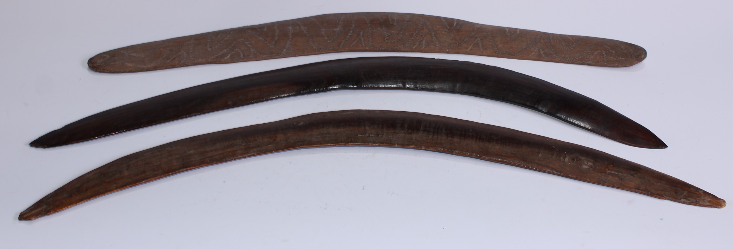 Tribal Art - an Australian Aboriginal boomerang, stone carved with meandering motifs, 66cm long, 19th century; others (3)