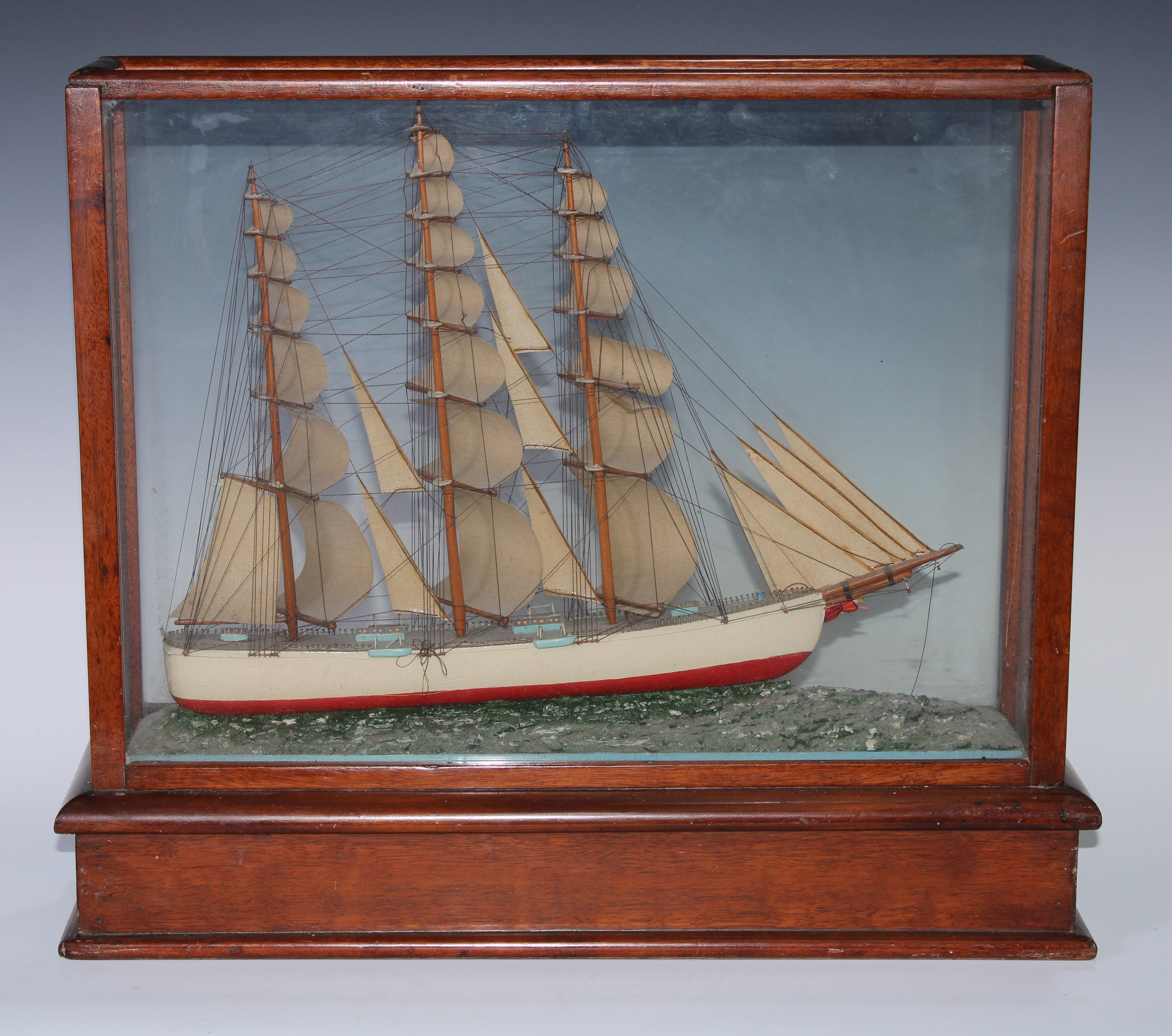 Martime and Marine Interest - an early 20th century scratch-built model ship, the three-masted clipper mounted in-the-round upon a choppy sea, glazed mahogany case, 43.5cm high, 51cm wide, c.1900