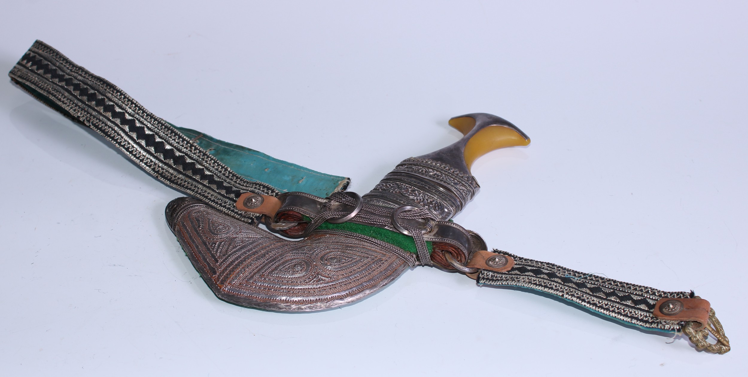 A Middle Eastern silver coloured metal mounted jambiya, 15cm curved blade, filigree scabbard, 28cm long overall