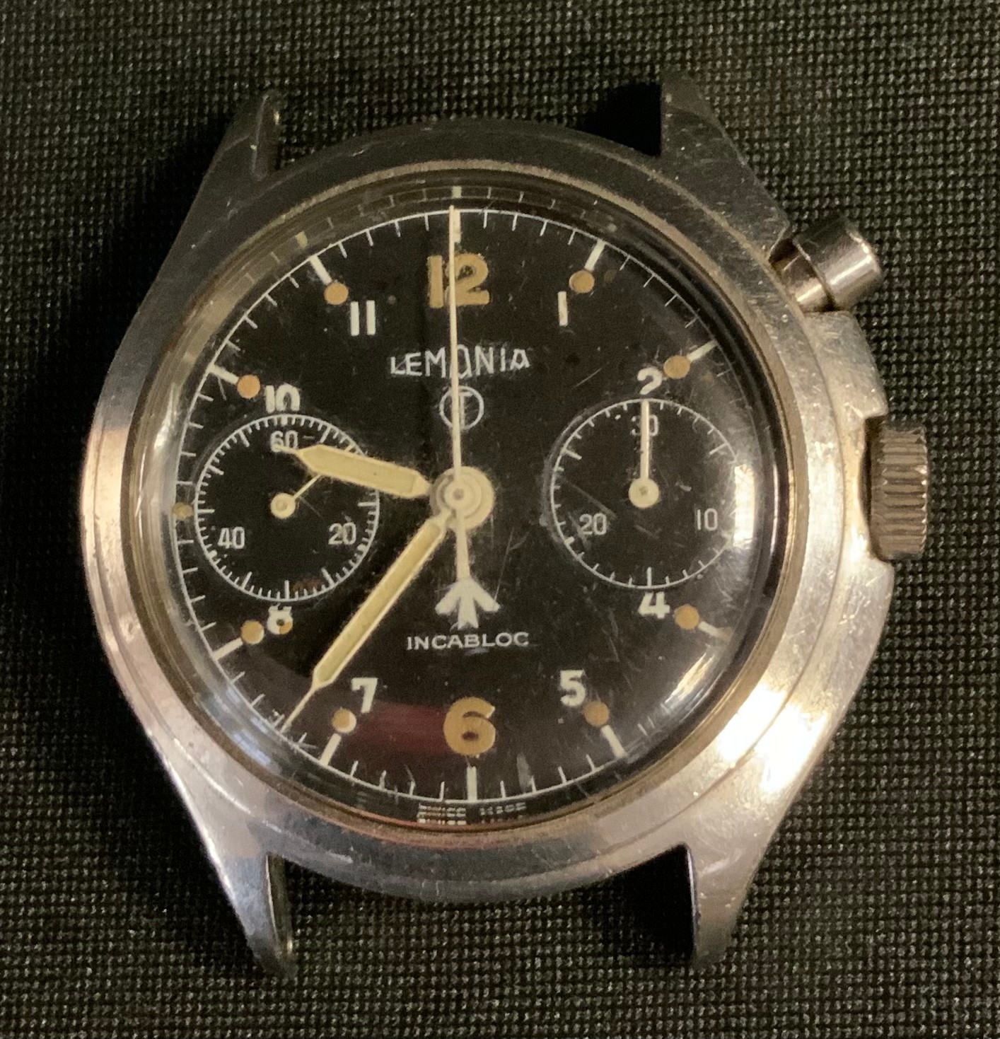 Post war British Army Lemania single button Chronometer watch head, black dial, twin subsidiary registers, Arabic numeral and dot baton markers, centre seconds, stainless steel case, marked 0552/924-3306, 658 beneath broad arrow issue stamp, 40mm wide. (faults)