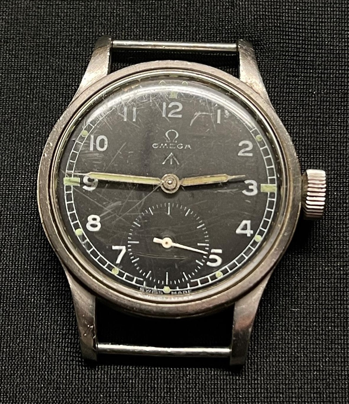 British Army issue Wristwatch by Omega. Case marked WWW (Watch Wristlet Waterproof) along with WD Broad Arrow plus Y23733 and 10687932. Black dial with Arabic numerals Luminous hand and markings to numbers. Separate seconds dial. Marked with trade mark plus "Omega" and "Swiss made". Replacement strap. Part of the so called "Dirty Dozen".