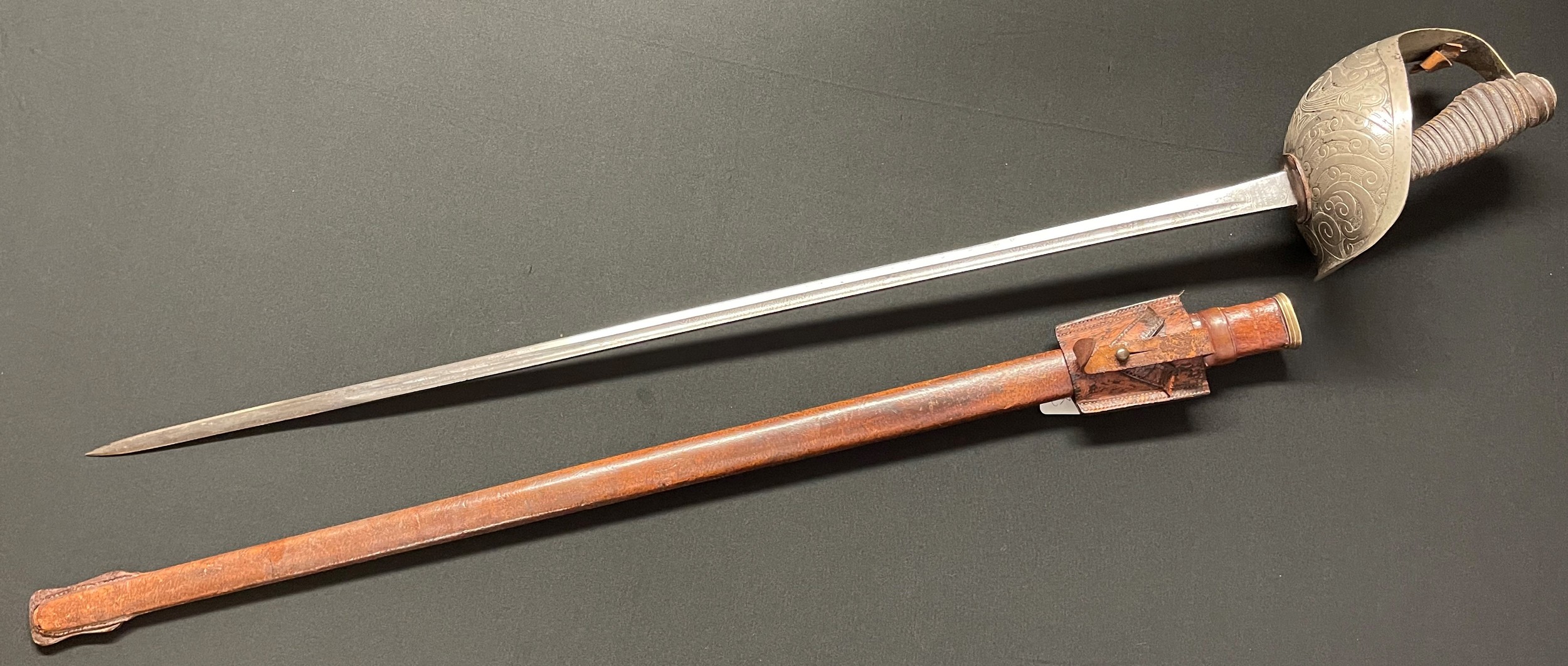 WW1 British 1912 Pattern 15th Kings Hussars officer's cavalry sword with single edged fullered blade 890mm in length. Proof marked and maker marked "Henry Wilkinson, Pall Mall, London" and serial numbered to spine of blade "48167". Etched design to blade and dedicated to "XVKH" "ABS" along with GRV Crown. Full guard with wire bound shagreen grip. Overall length 1095mm. Remains of knot present. Complete with scabbard with brown leather cover and brown leather frog, straps missing.