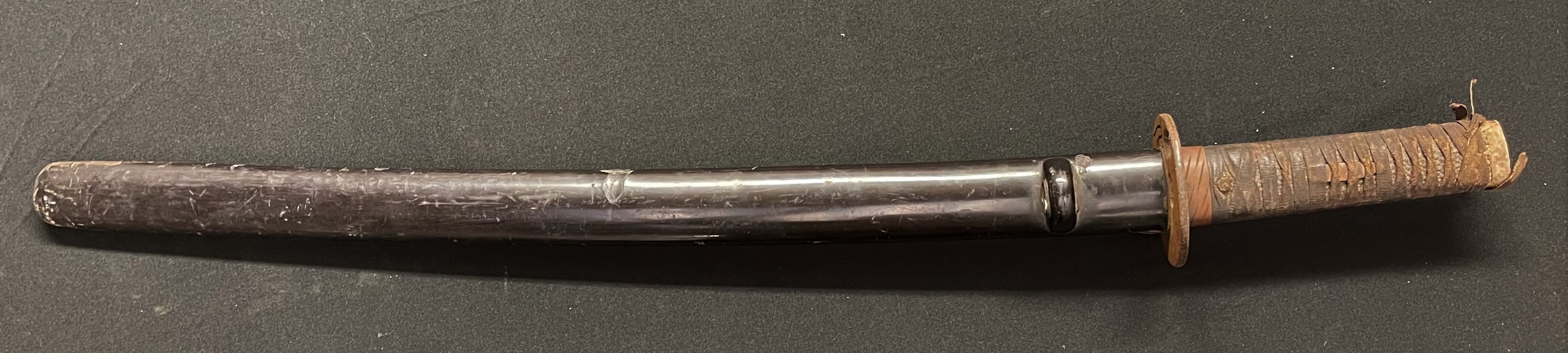 A Japanese Wakisashi sword with 510mm long blade, tang is un-signed. Iron Tsuba. Overall length 690mm. Complete with laquered Saya scabbard.