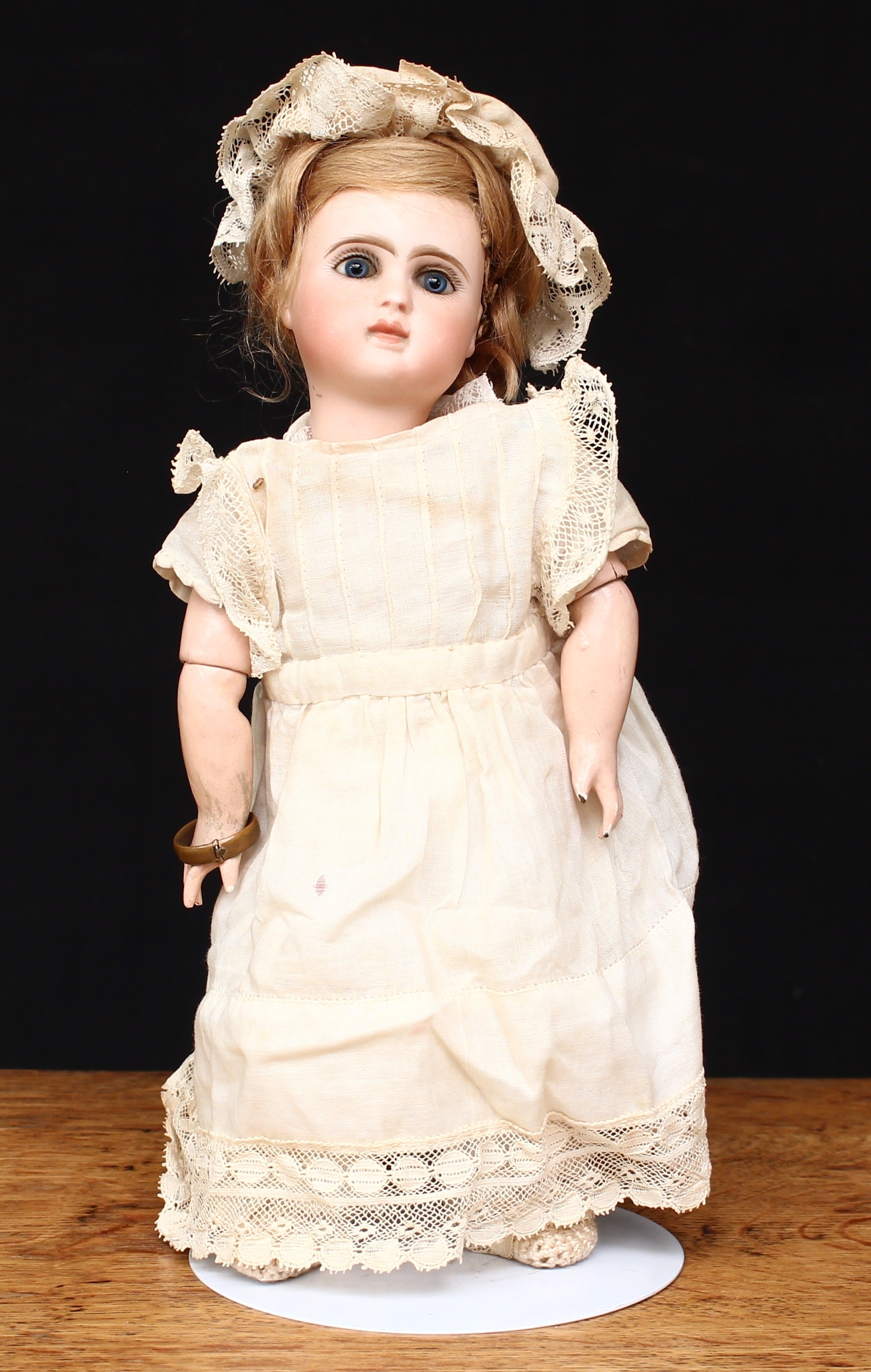 A French bisque head and composition bodied doll, fixed inset blue glass eyes, painted features including fine eyelashes and brown feathered eyebrows, blonde wig, impressed and printed marks 'LE PARARISIEN A34 PARIS', 26cm high, probably by Jules Nicholas Steiner (France)